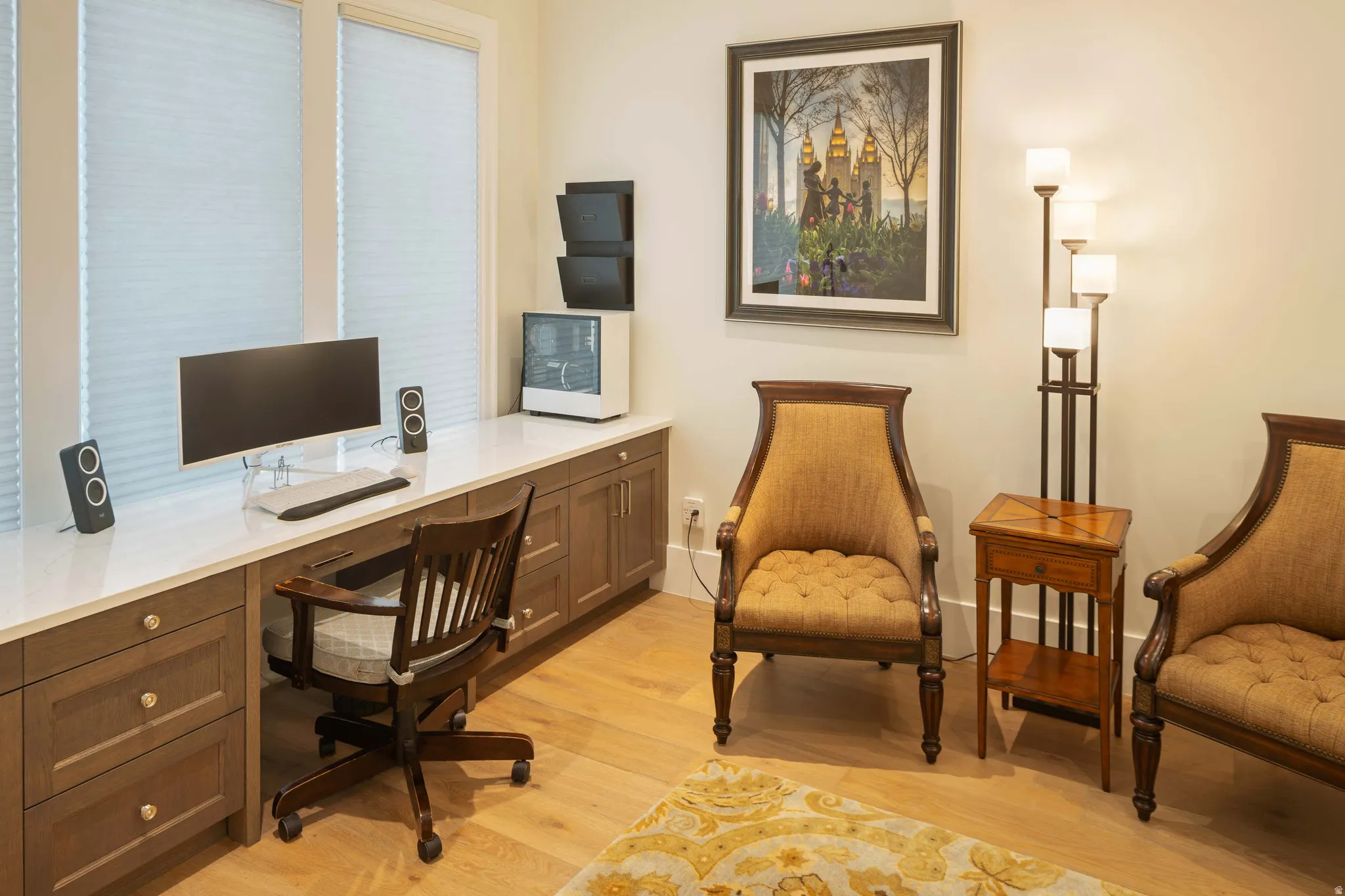 Dedicated workspace featuring an integrated desk with a white countertop and wood-finish cabinetry