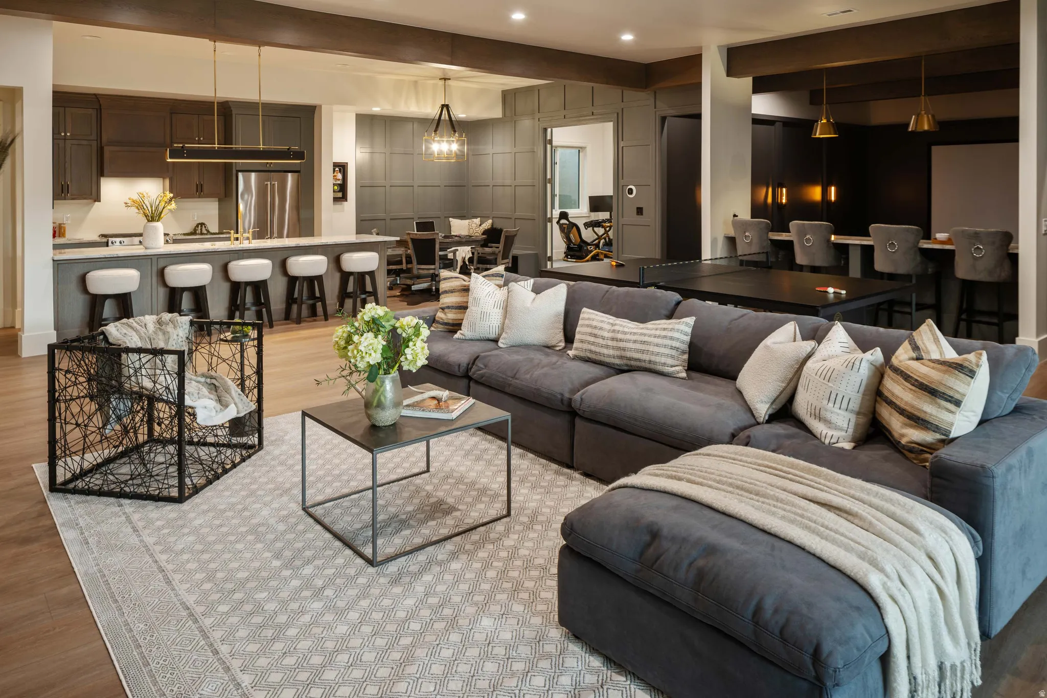 Spacious entertainment area featuring wood-finish flooring, a contemporary sectional, and an open-concept kitchen with a breakfast bar