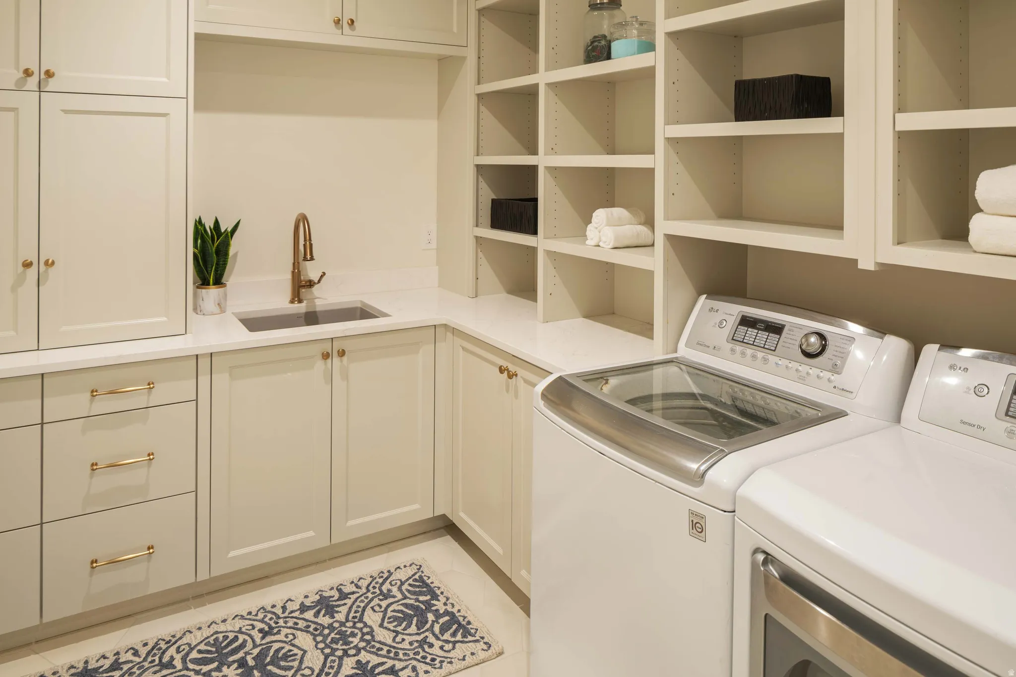 Utility room featuring built-in cabinetry, an integrated sink with a bronze-finish faucet, extensive open shelving, and a durable countertop surface