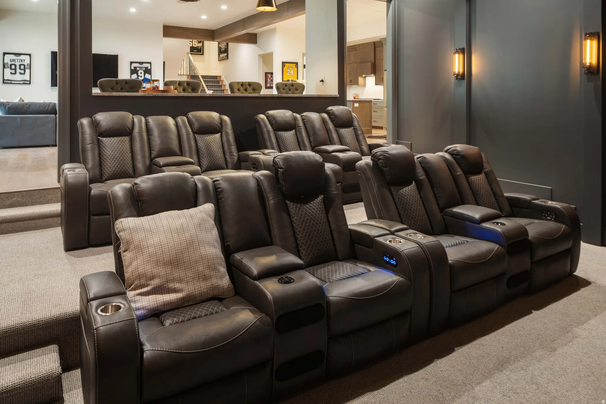 Theater room featuring multi-tiered seating, wall-mounted sconces, and recessed lighting