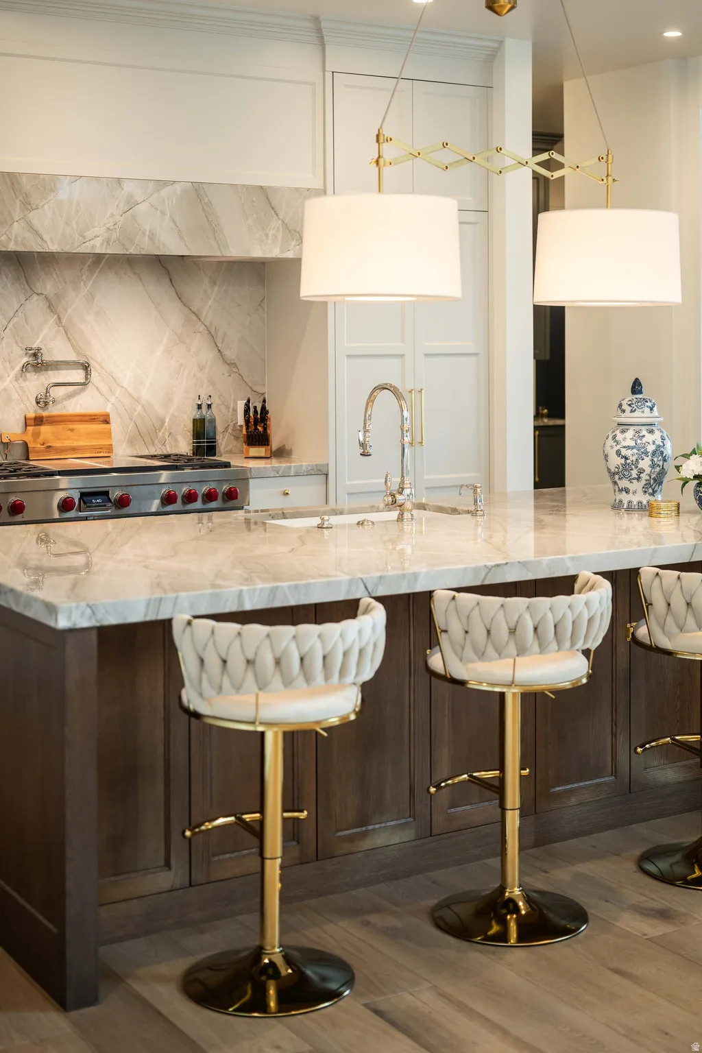 Kitchen island featuring a substantial stone countertop, integrated sink with gooseneck faucet, and dark wood-finish cabinetry