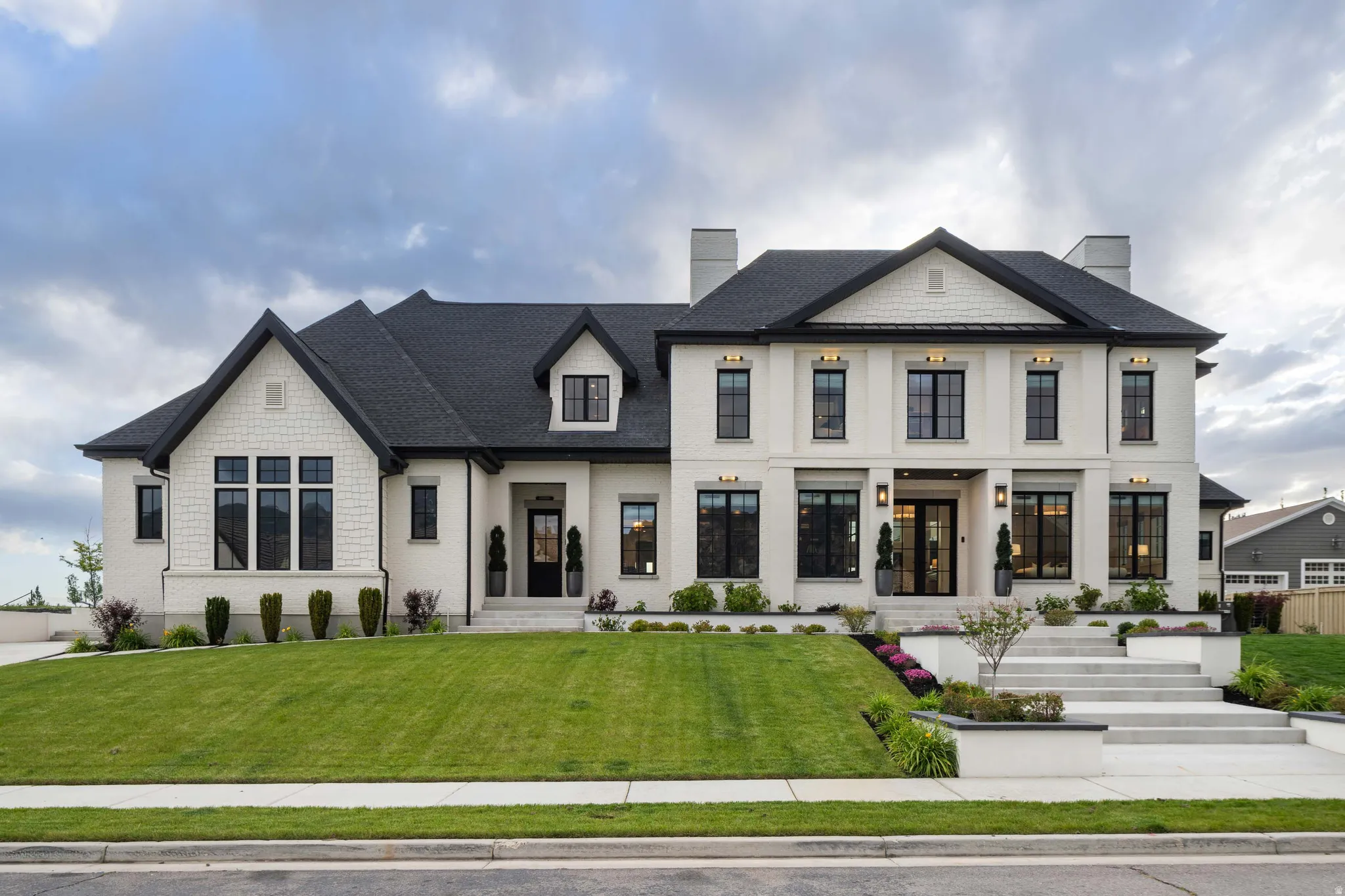 Contemporary residence featuring a light-colored brick facade with dark window frames and a contrasting dark roof
