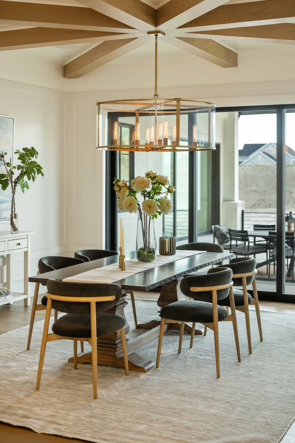 Dining area featuring a prominent chandelier, coffered ceiling with wood beams, and expansive sliding glass doors