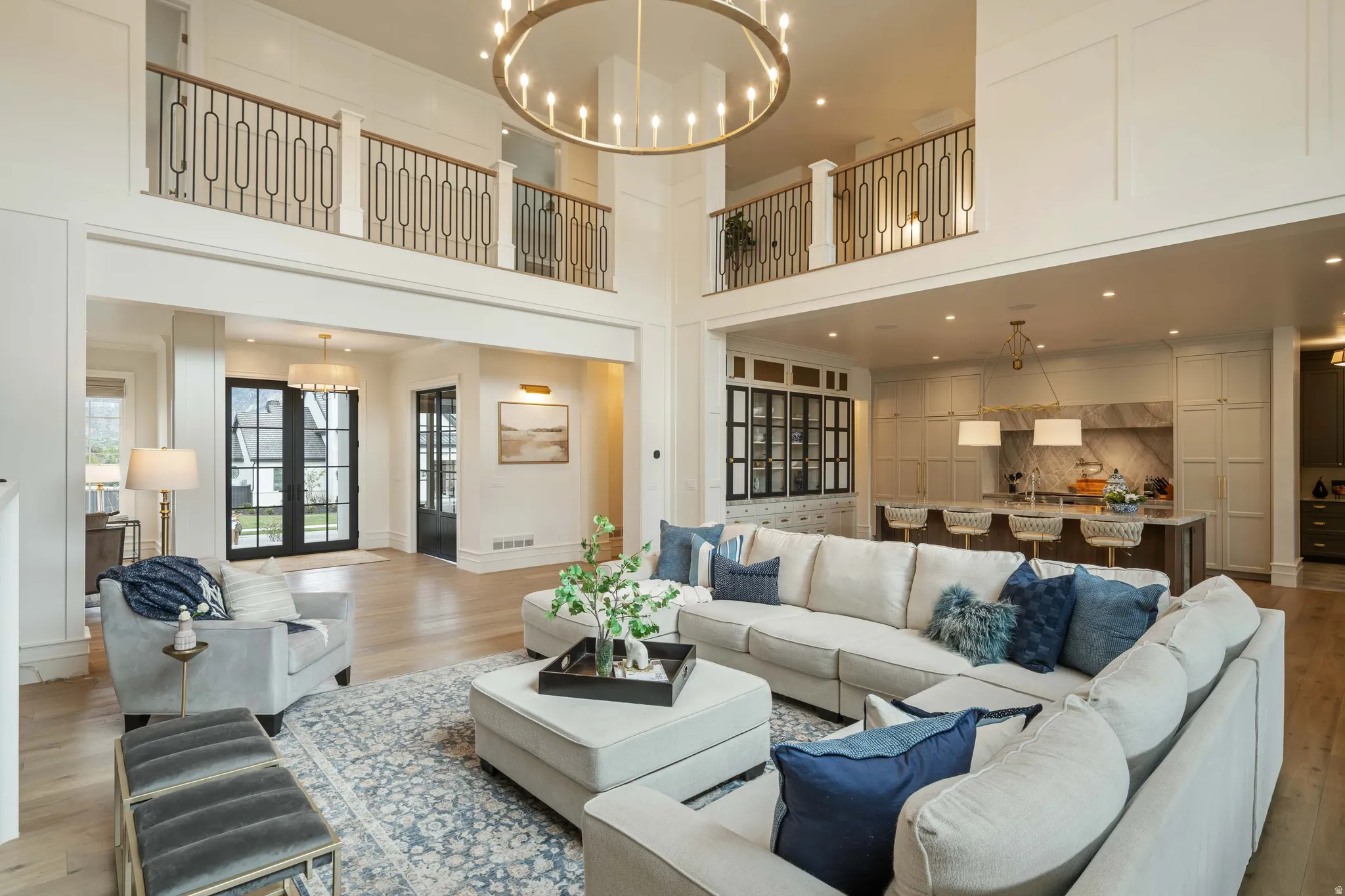Two-story living area with double-height ceilings, a large chandelier, and wood-finish flooring