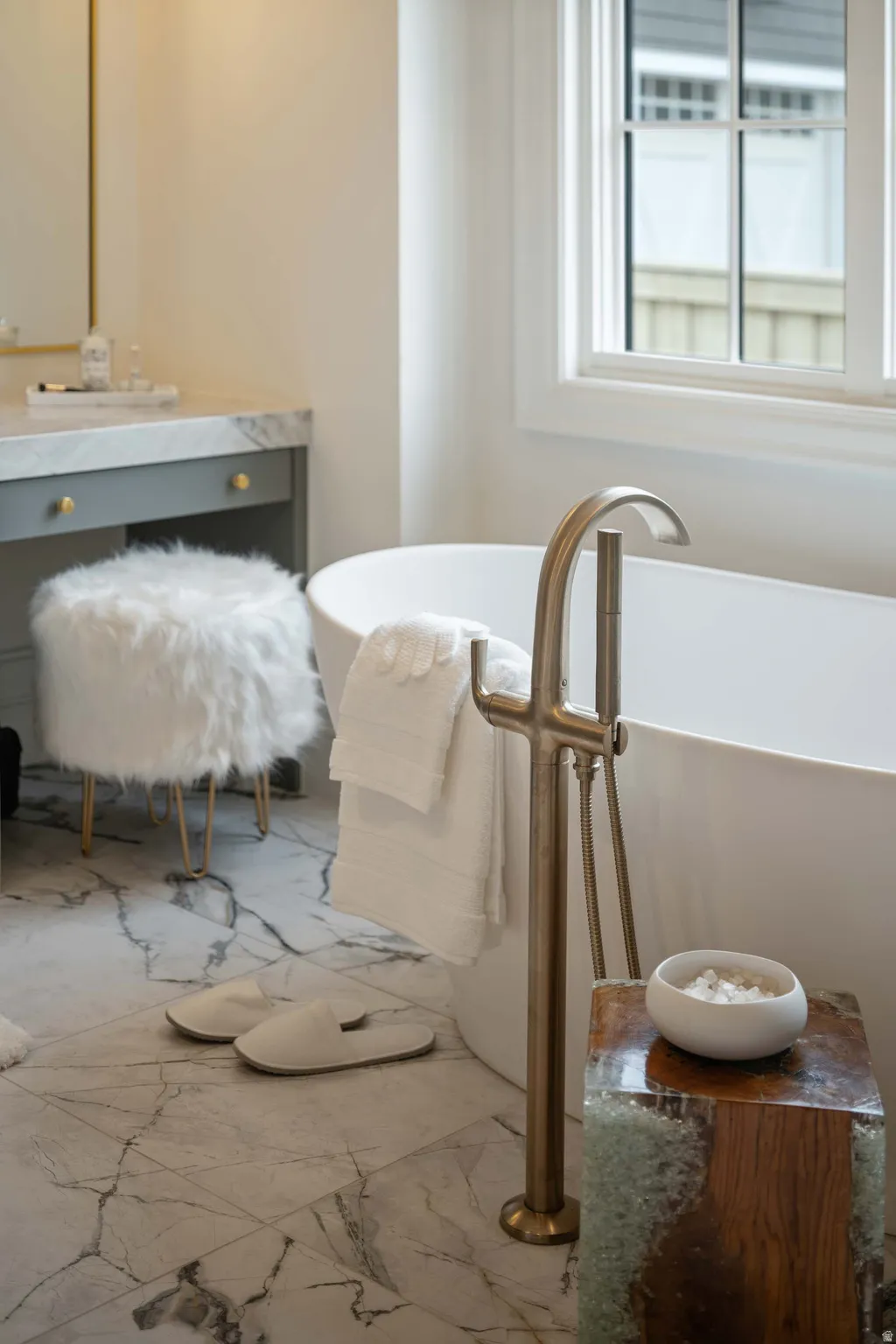 Freestanding soaking tub with floor-mounted brushed metal faucet