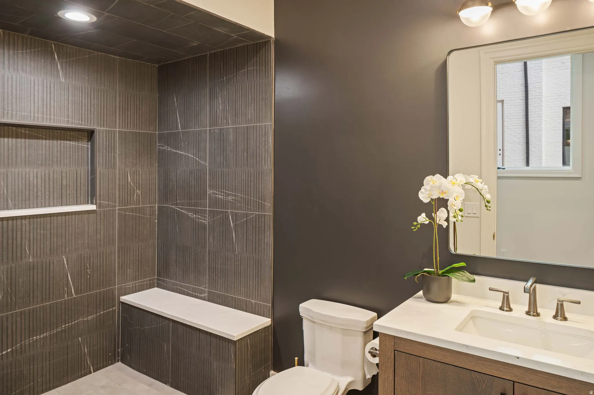 Bathroom featuring a walk-in shower with textured tile, recessed lighting, and a built-in bench