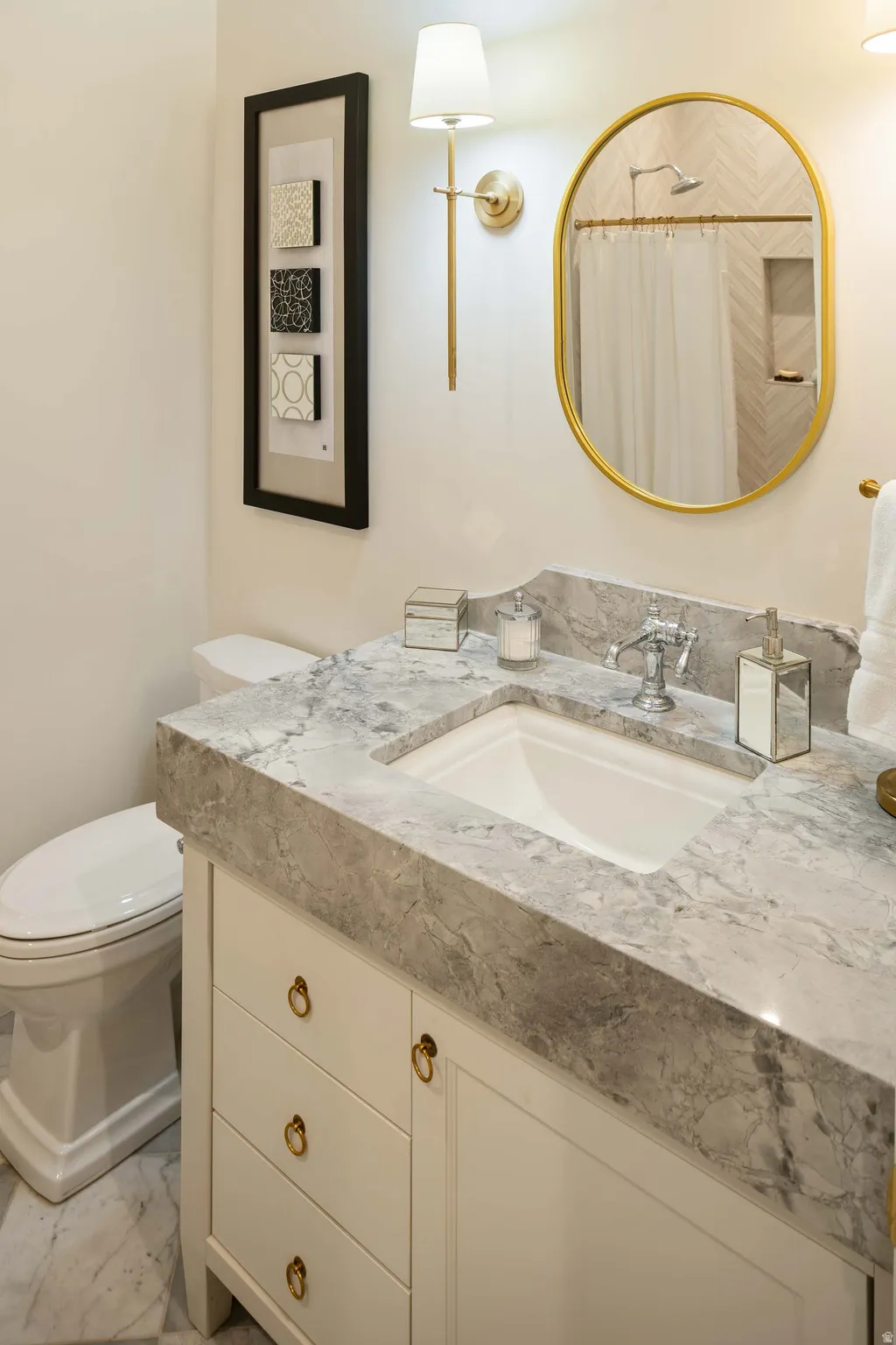 Bathroom vanity with a gray veined countertop, an undermount sink, and a chrome faucet