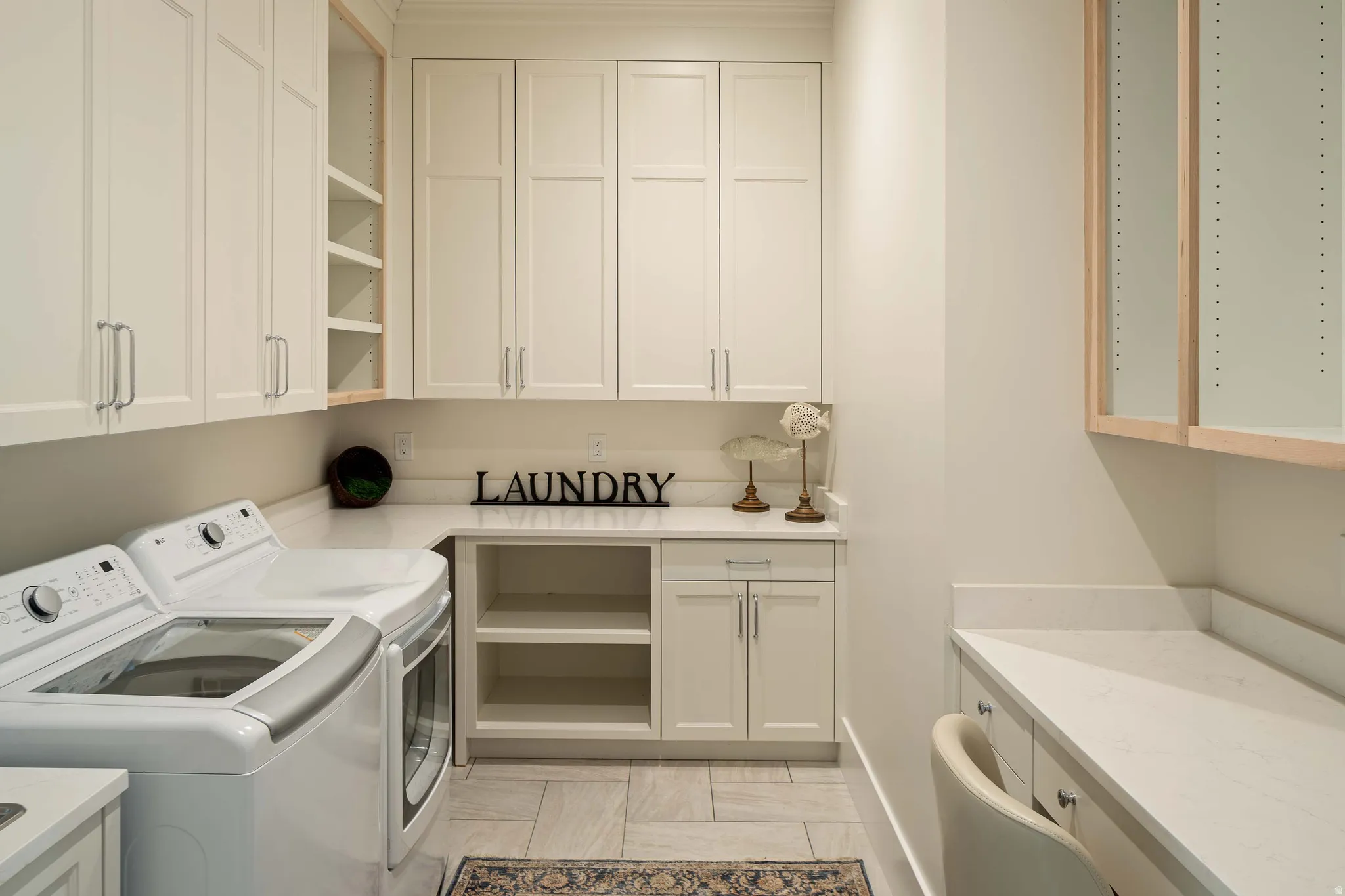 Dedicated utility room featuring white shaker-style cabinetry, extensive countertop space, and light-toned tile flooring