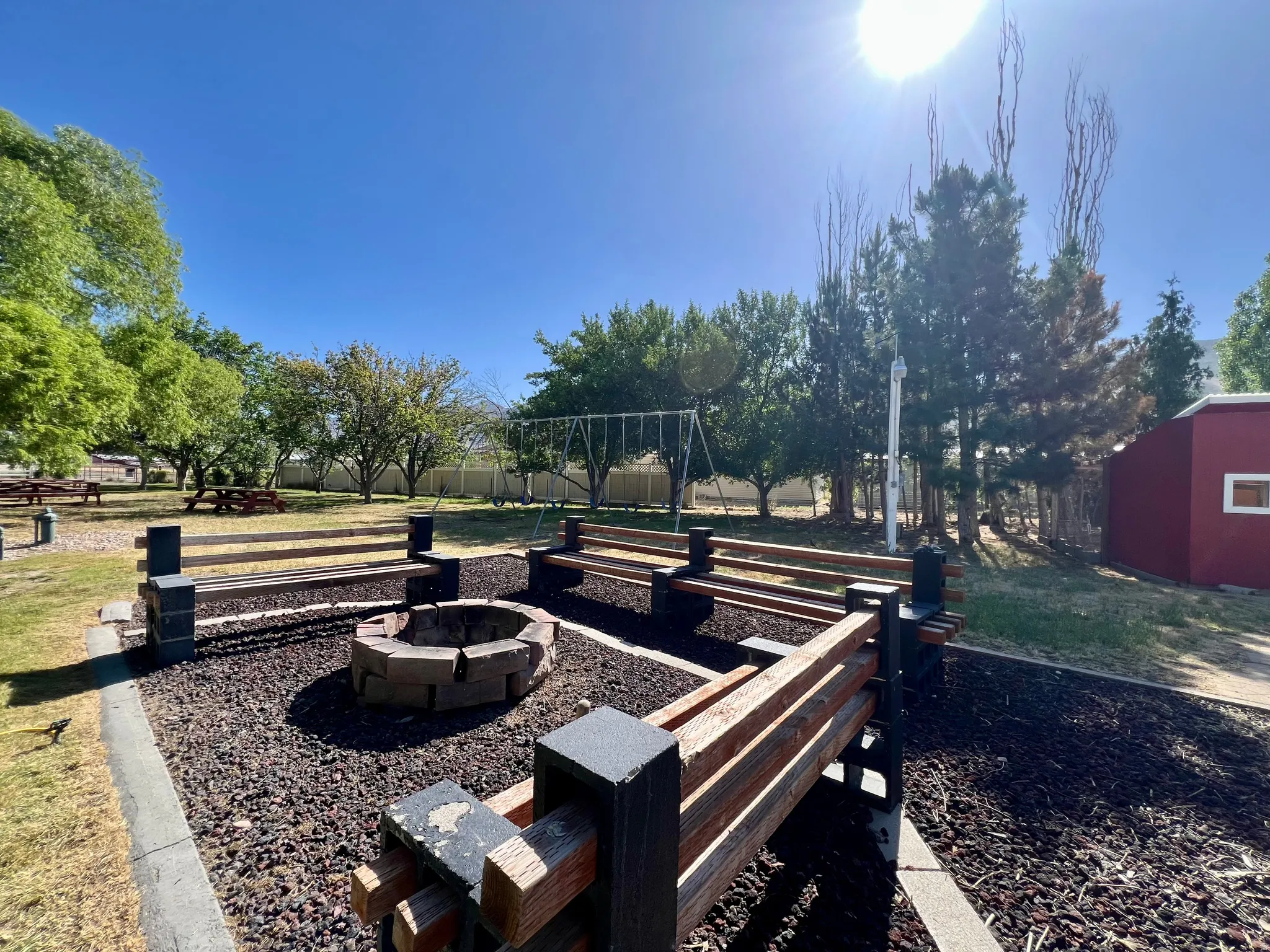 Outdoor fire pit surrounded by built-in wooden seating, featuring a gravel base and perimeter landscaping