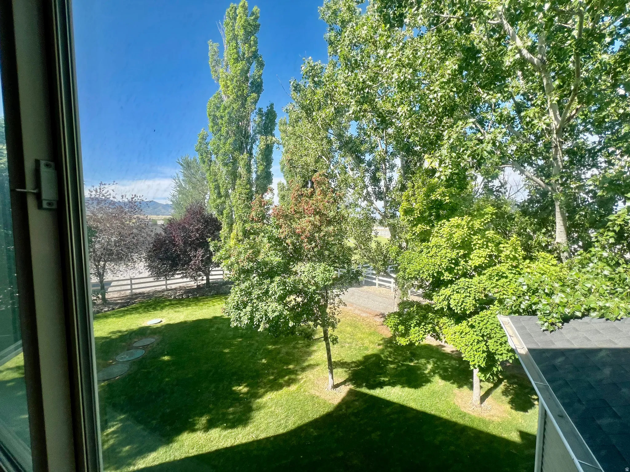Lush green lawn with stepping stones, bordered by a white fence