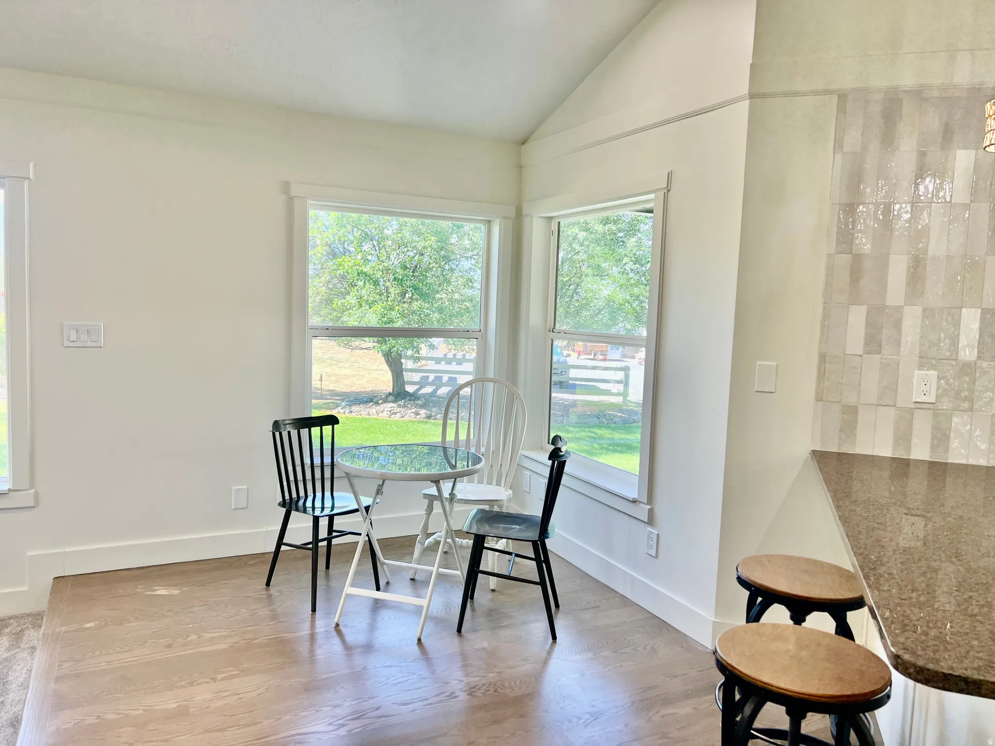 Bright dining nook featuring large windows, wood-finish flooring, and crisp white baseboards
