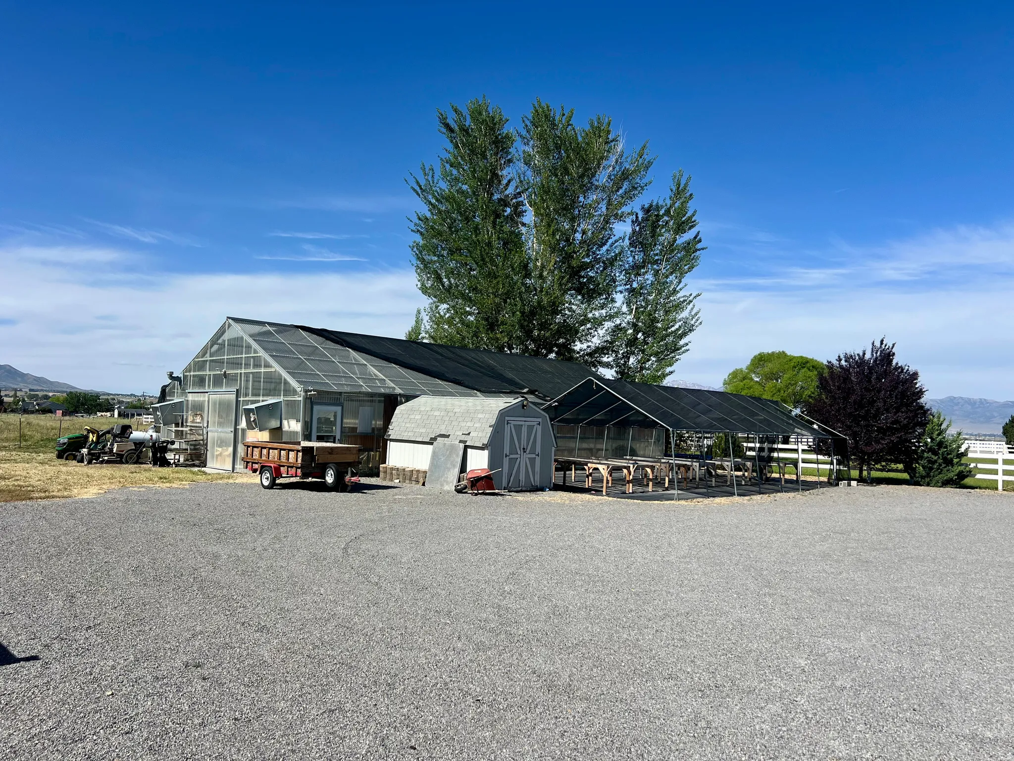 Expansive gravel parking area with multiple large greenhouse structures
