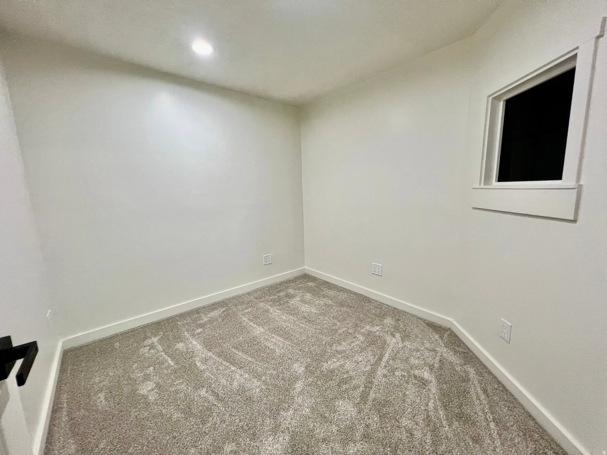 Room featuring neutral wall finishes, light-toned carpeting, a recessed ceiling light, and a single window with white trim