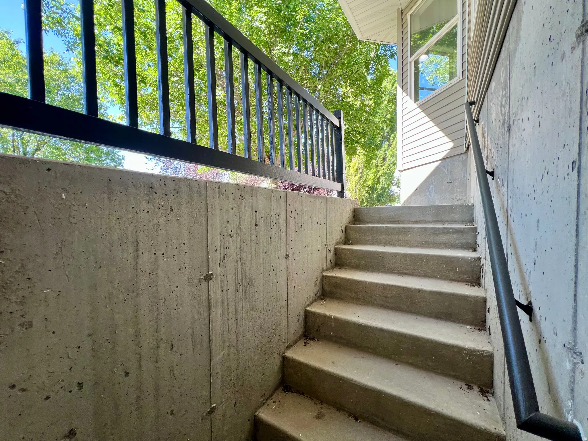 Concrete exterior stairs with a black metal handrail and a complementing black metal railing