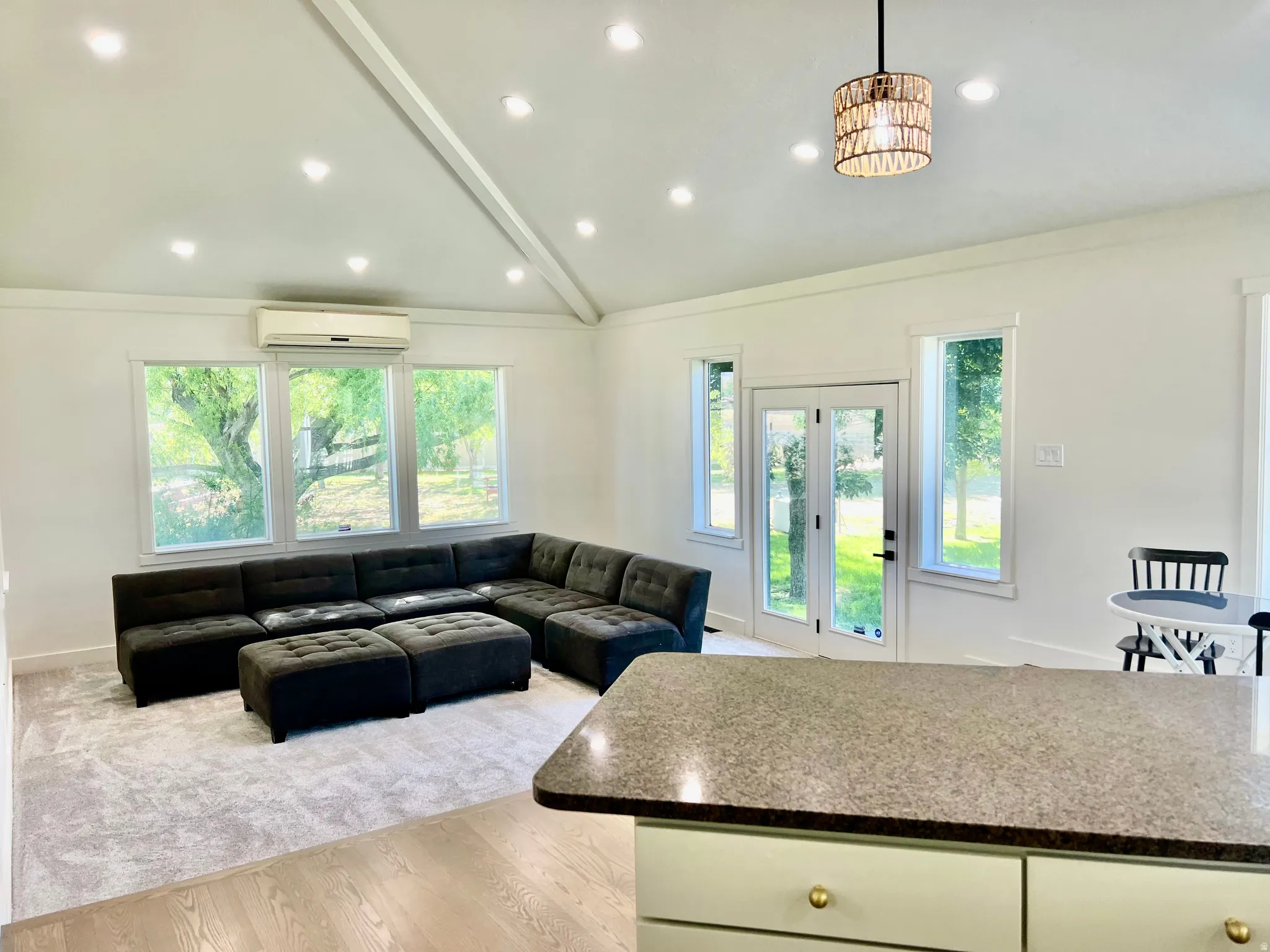 Vaulted ceiling with recessed lighting and a decorative pendant fixture