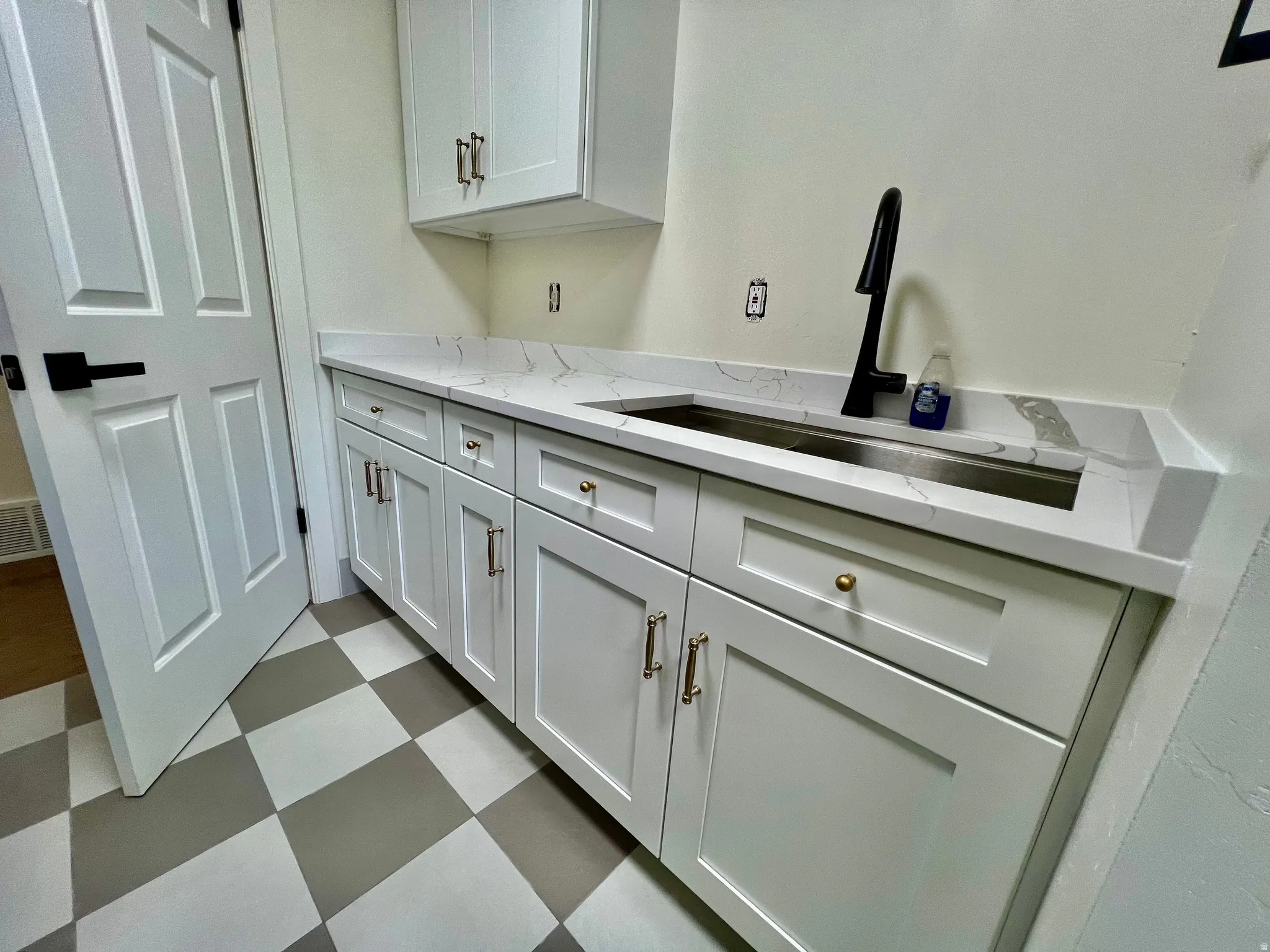 White shaker cabinetry with gold and bronze hardware, featuring a modern matte black faucet and stainless steel sink