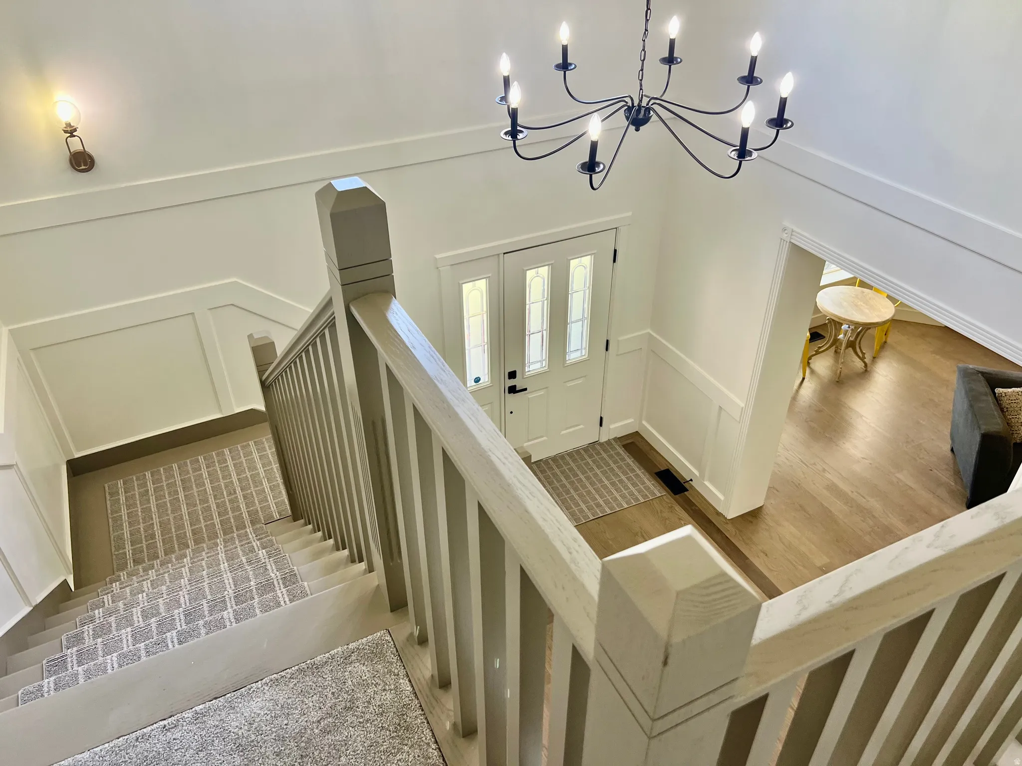 Entry foyer featuring a white paneled door with glass inserts, a black chandelier, and light wood-finish flooring