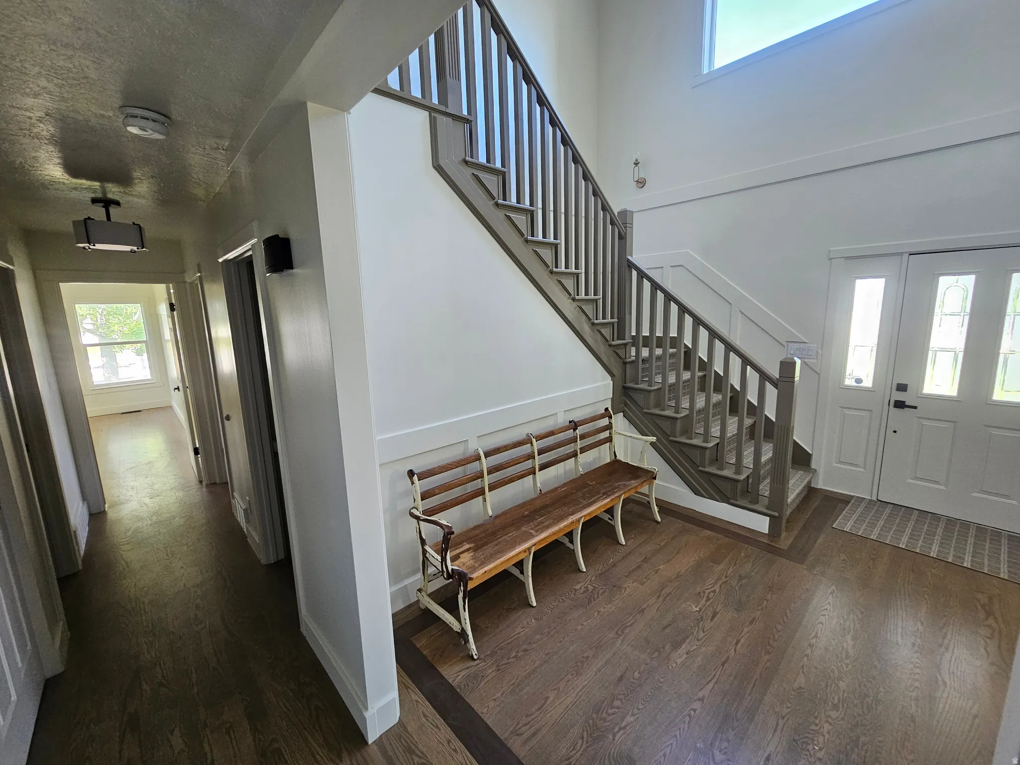 Two-story foyer featuring wood-finish flooring, a grand staircase with painted banister and newel post, and wainscoting