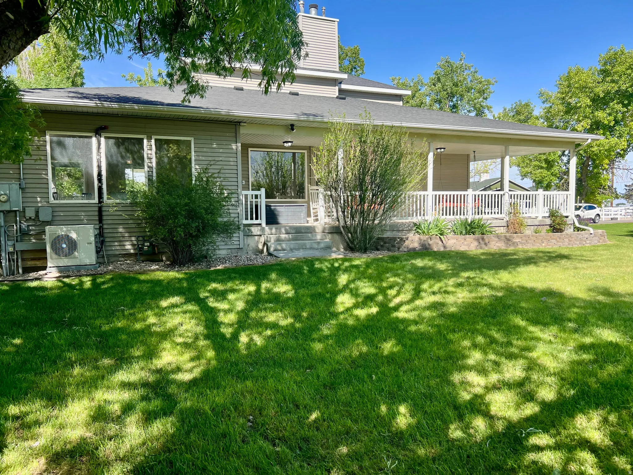 Expansive green lawn with a covered porch featuring white railings