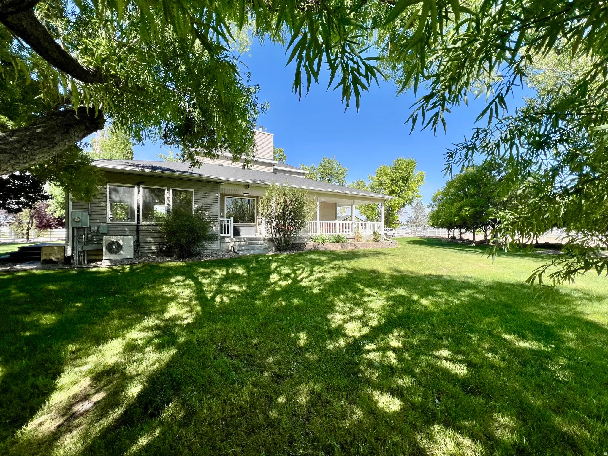 Expansive rear yard featuring a manicured lawn and mature trees