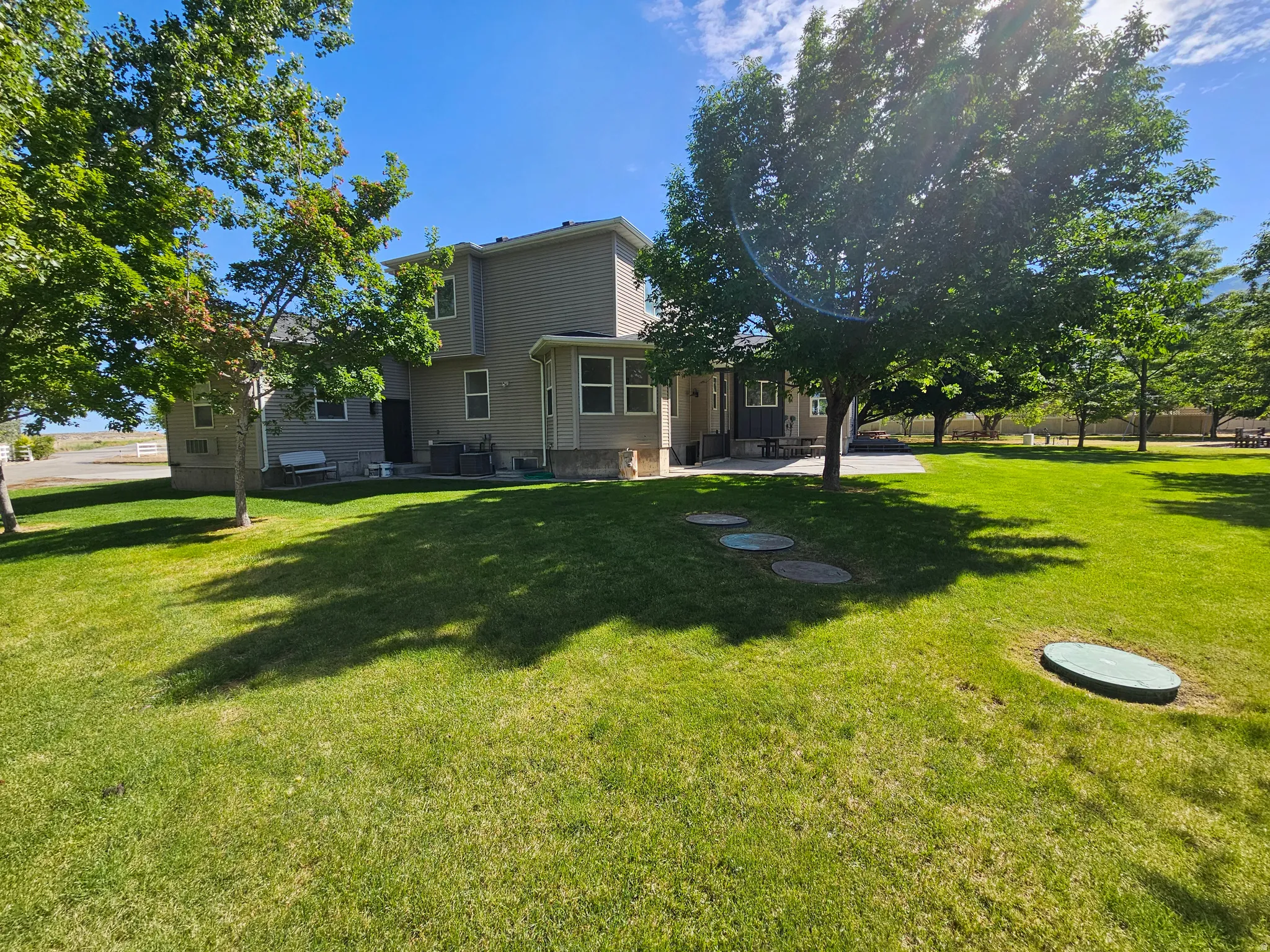 Expansive green lawn with mature trees providing natural shading