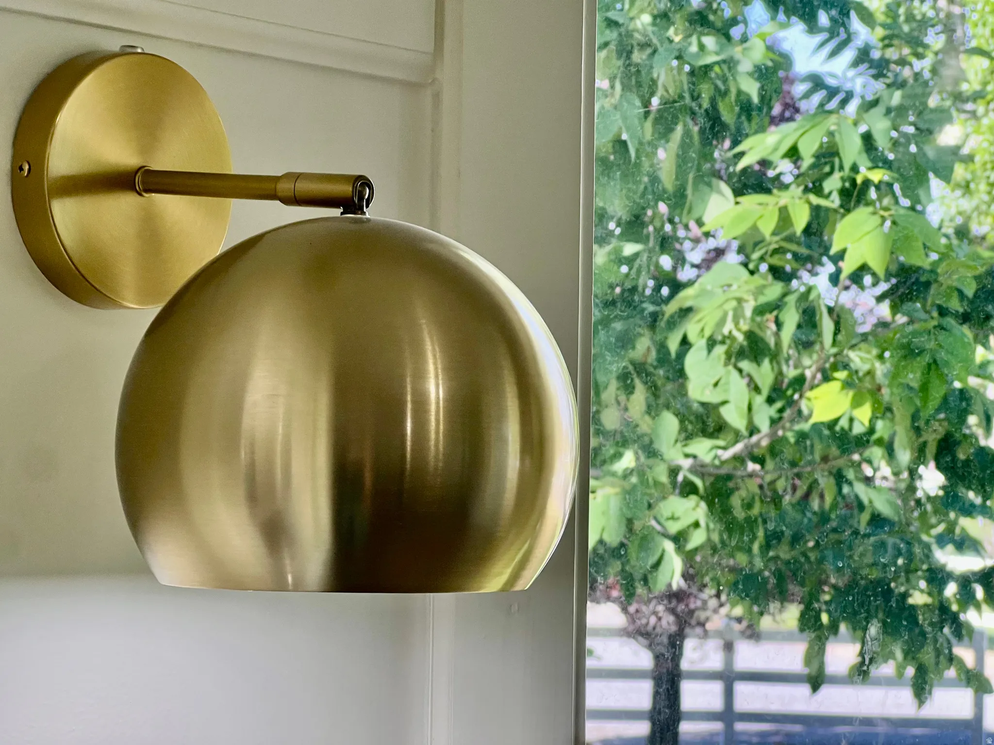 Contemporary brass wall sconce with a domed shade