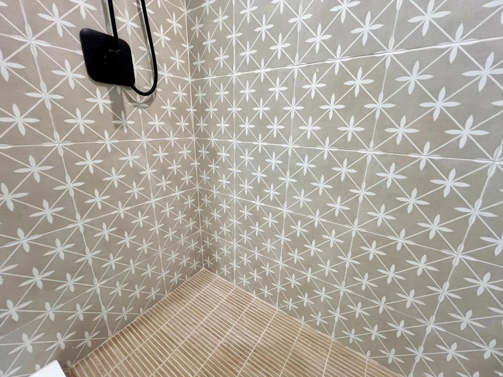 Shower enclosure featuring patterned wall tiles and a slatted shower pan