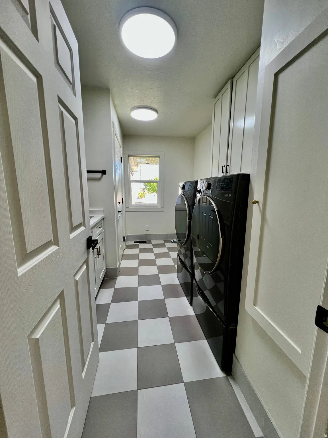 Laundry area featuring checkerboard flooring, a window providing natural light, built-in cabinetry, and recessed lighting