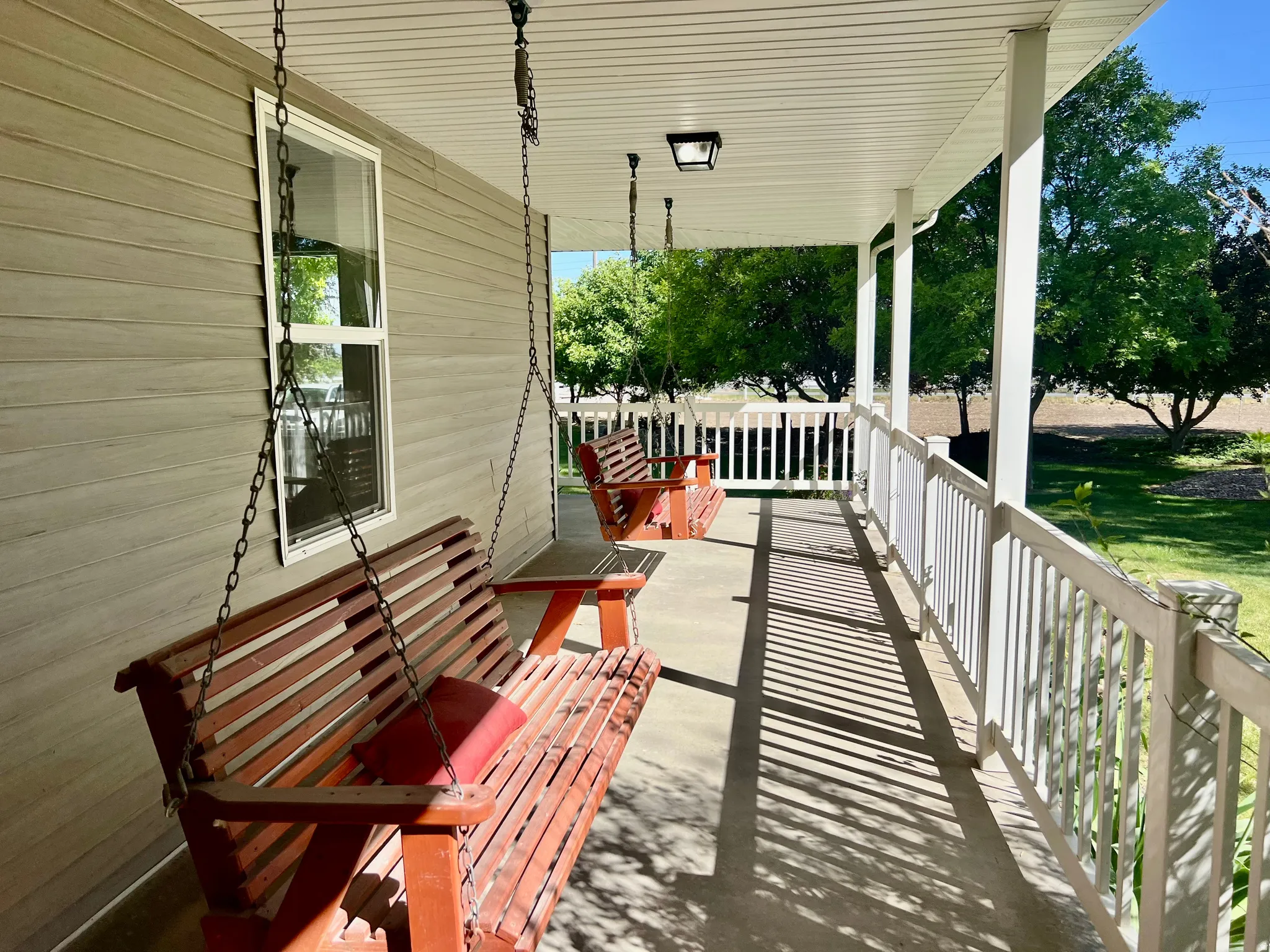 Covered porch with light-toned siding, white trim, and a white railing system