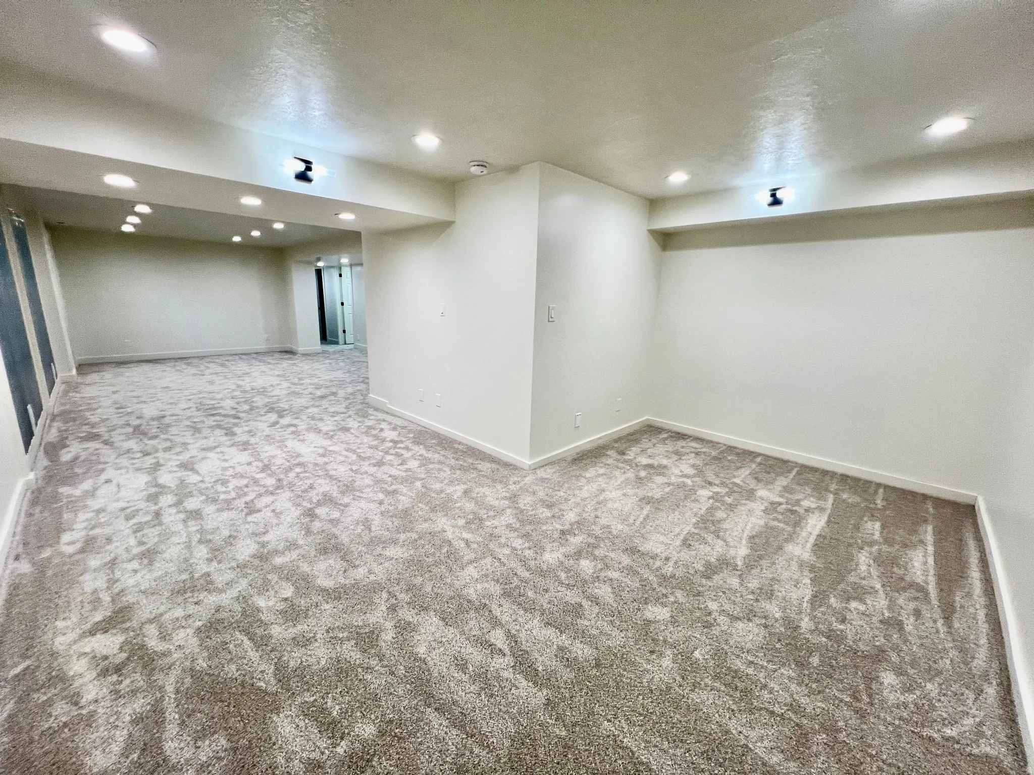 Spacious room featuring new carpeting, recessed lighting, white baseboards, and neutral wall finishes