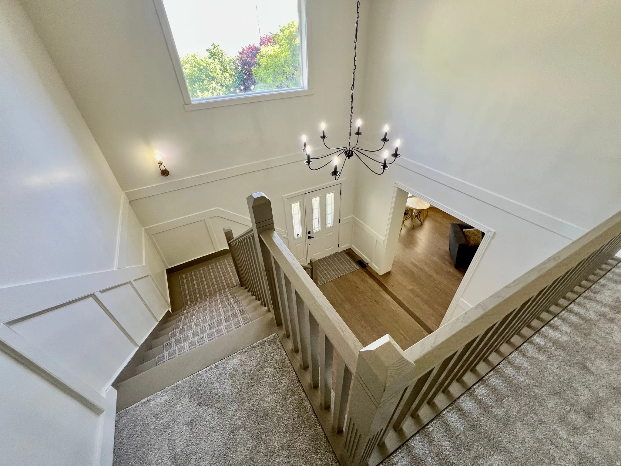 Two-story entryway featuring a black chandelier and wood-finish flooring with a contrasting inlay