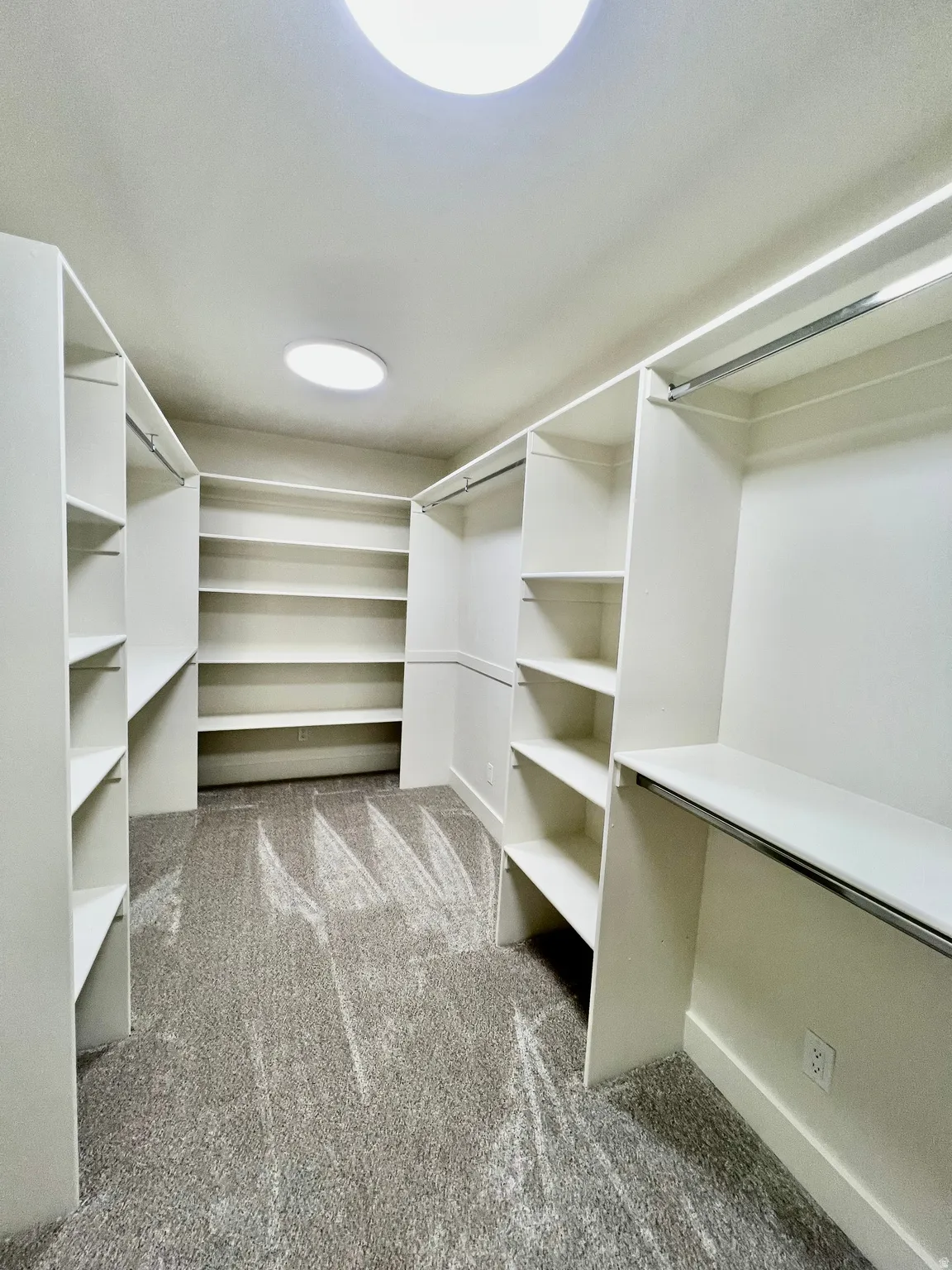 Walk-in closet featuring extensive built-in shelving, hanging rods, and recessed lighting