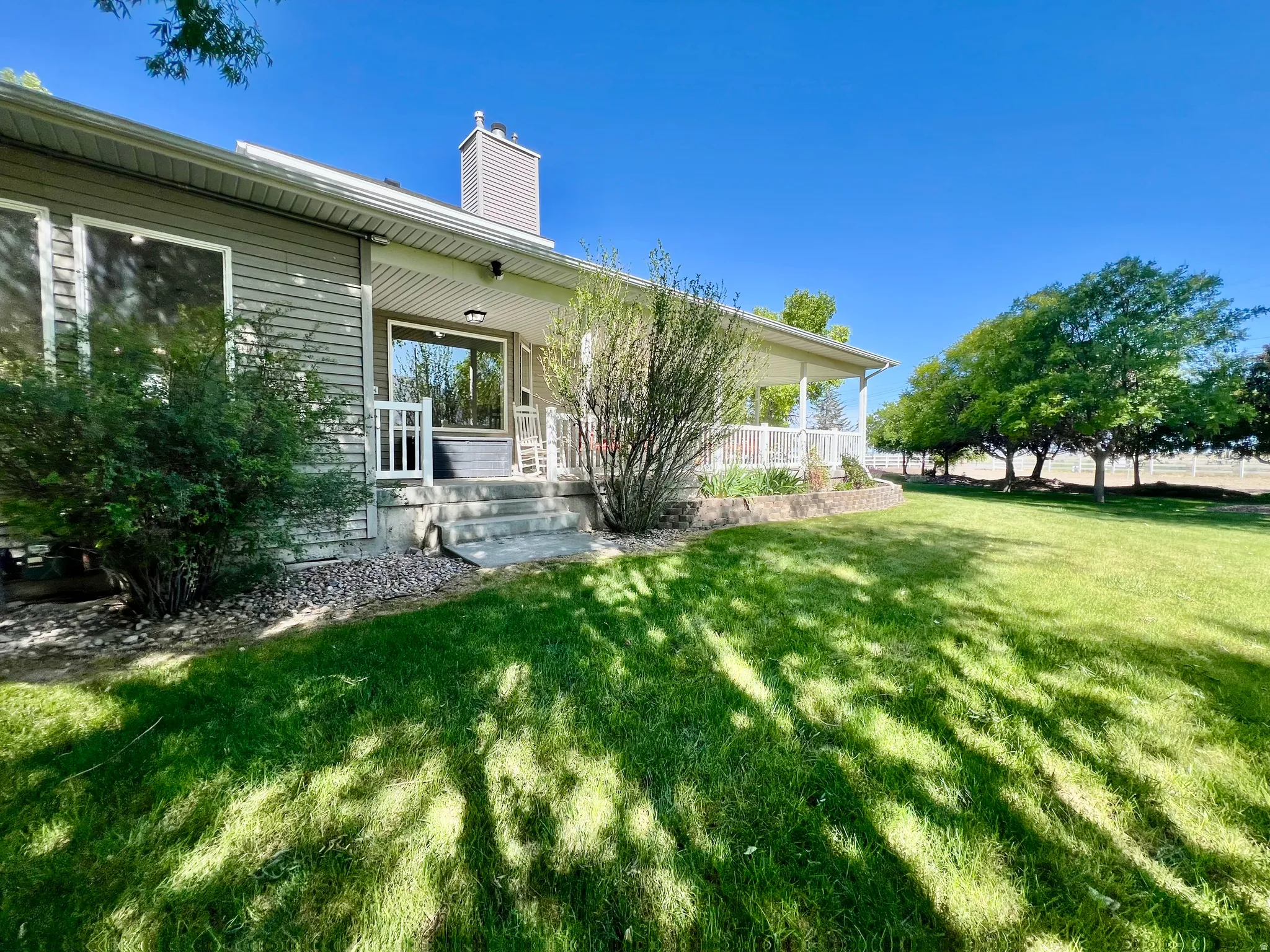 Spacious lawn bordered by mature trees and a fenced perimeter