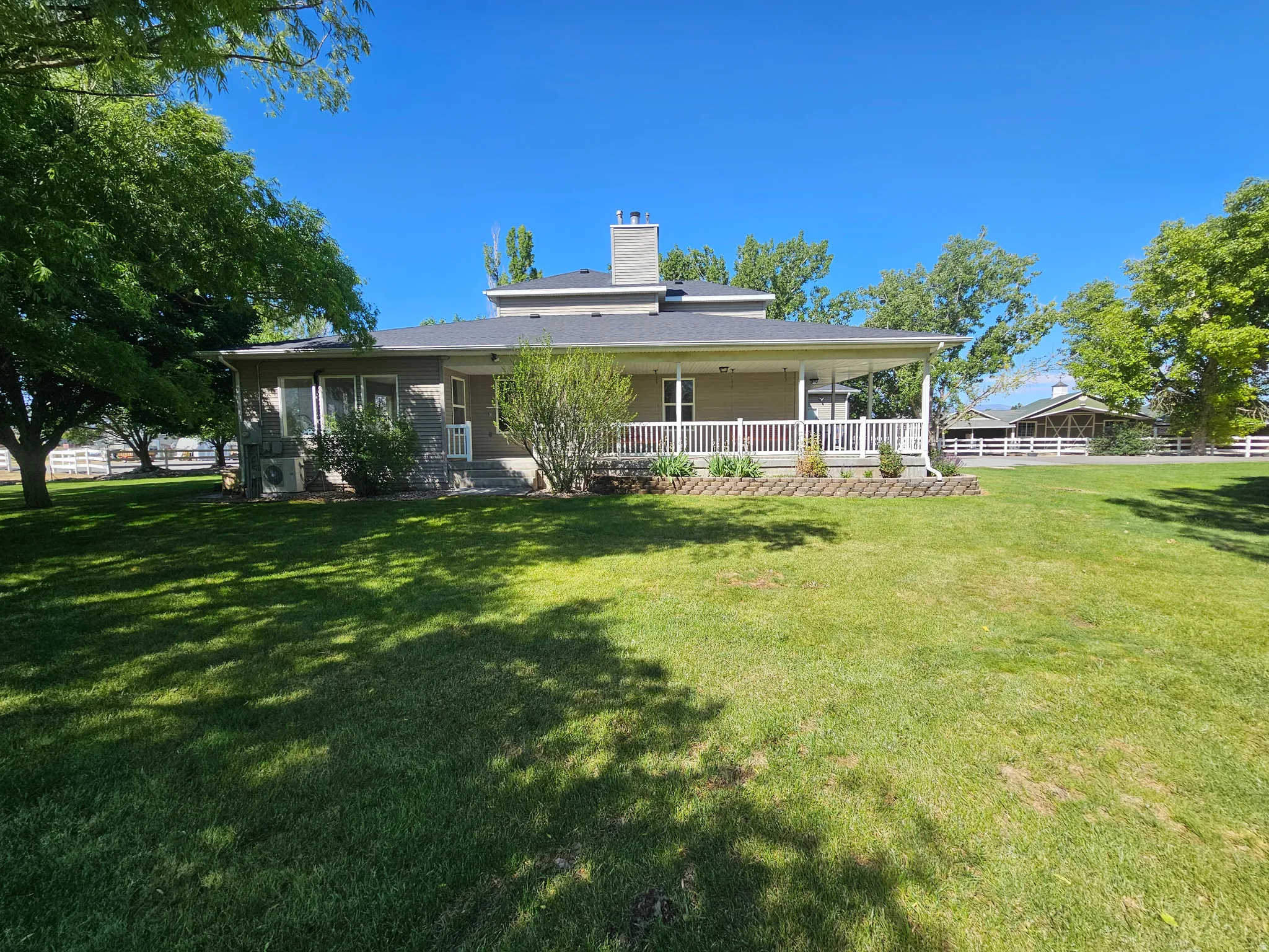 Expansive green lawn bordering a residence with a covered porch
