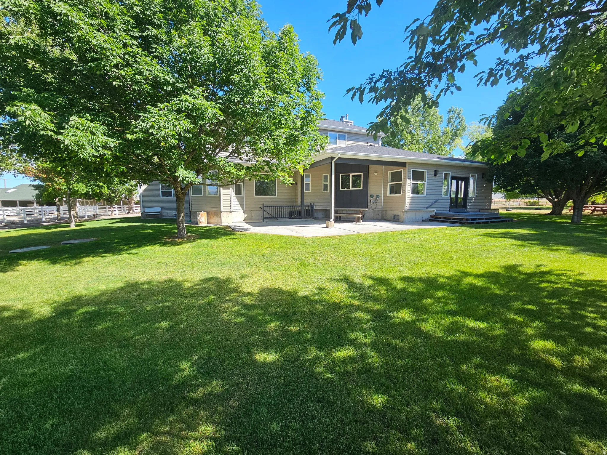 Expansive green lawn with mature trees and a concrete patio