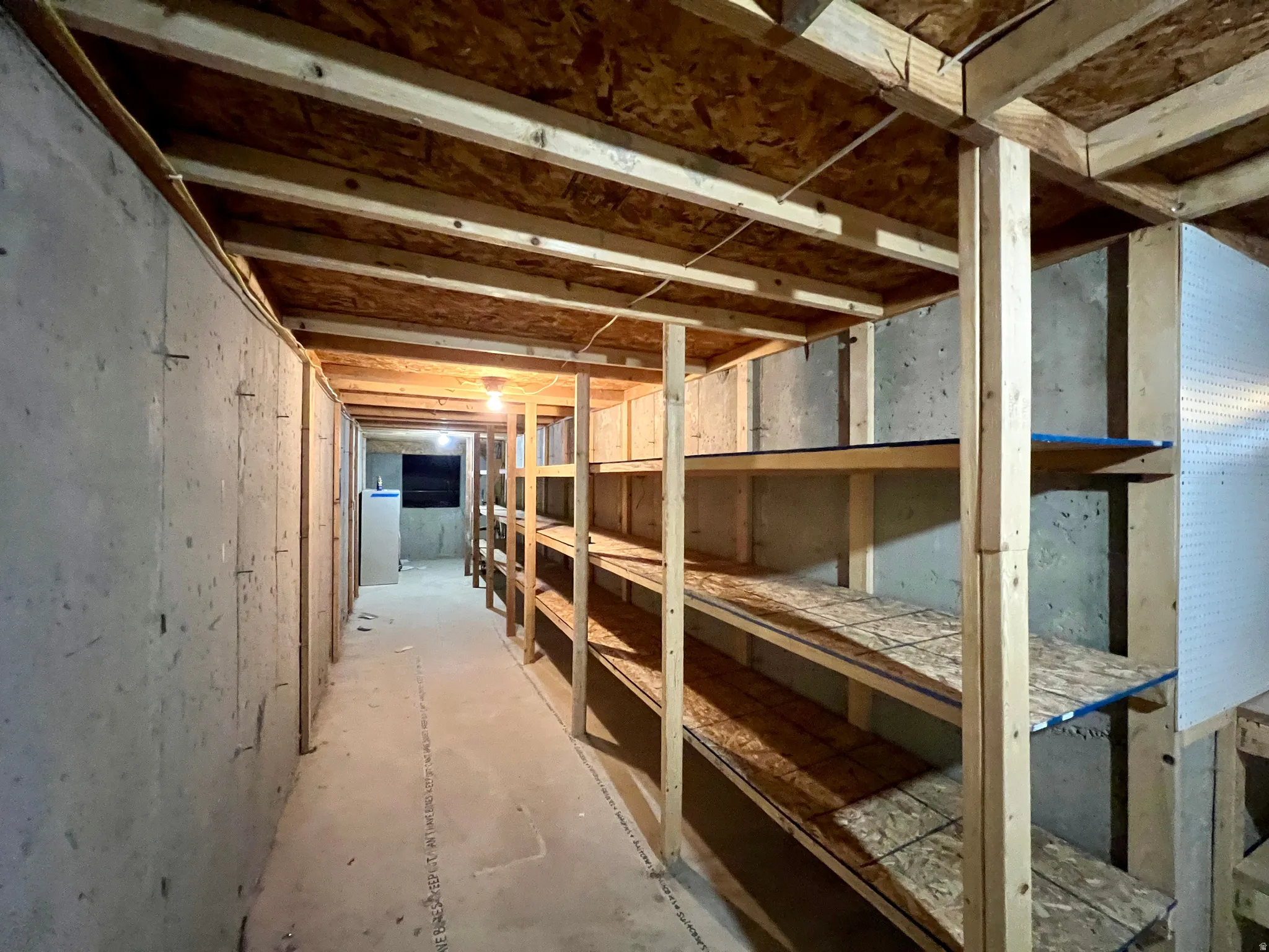Unfinished basement with concrete flooring and exposed wooden ceiling joists