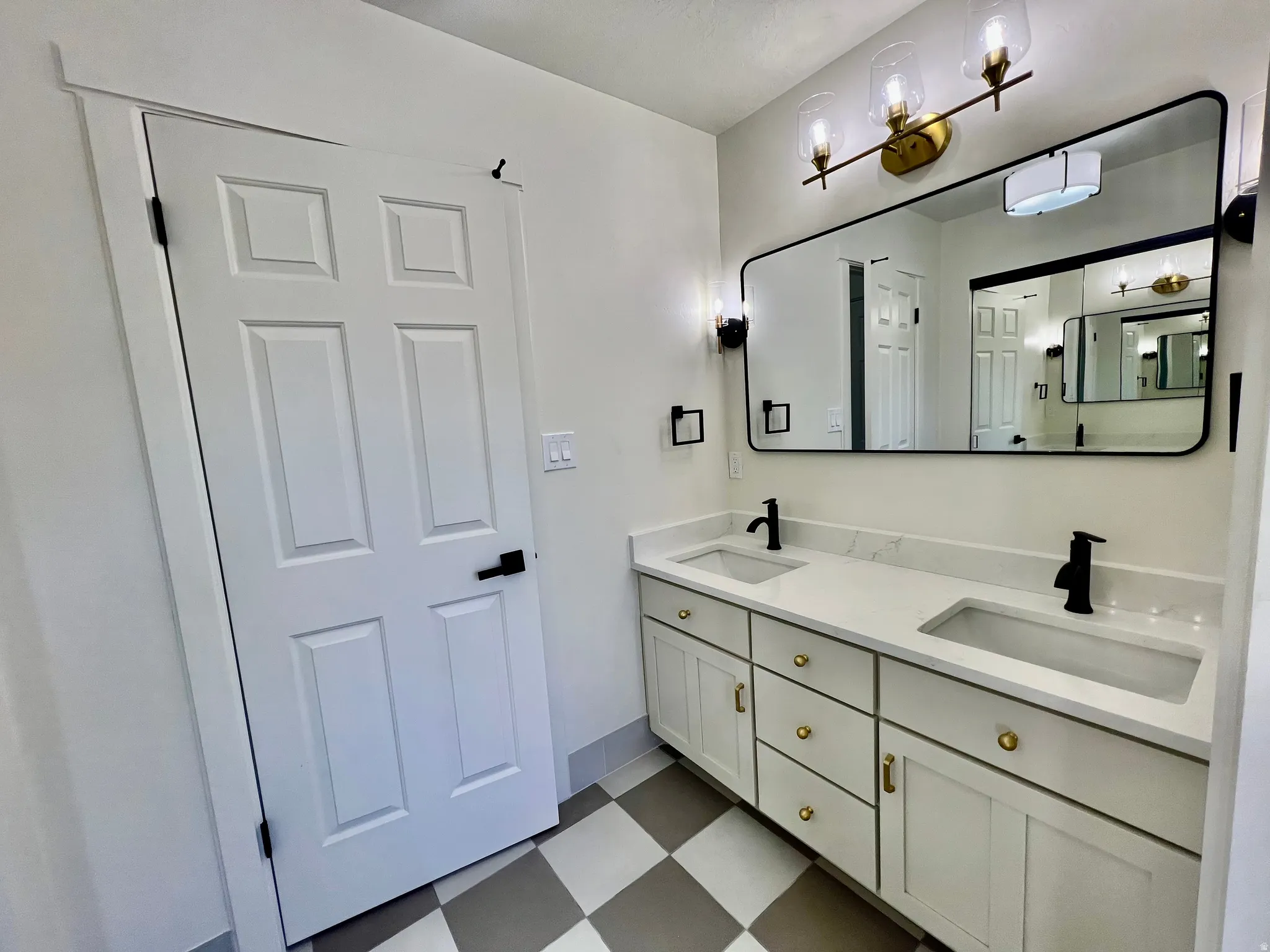 Double vanity featuring white cabinetry with gold-tone hardware, quartz countertops, and integrated rectangular sinks
