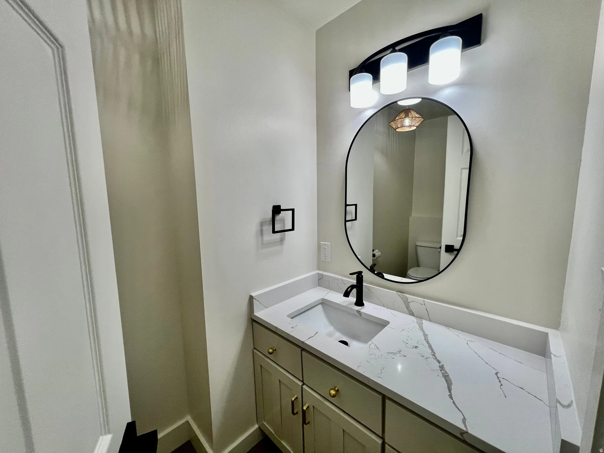Modern vanity with a white rectangular undermount sink, a stone-finish countertop, and a matte black faucet