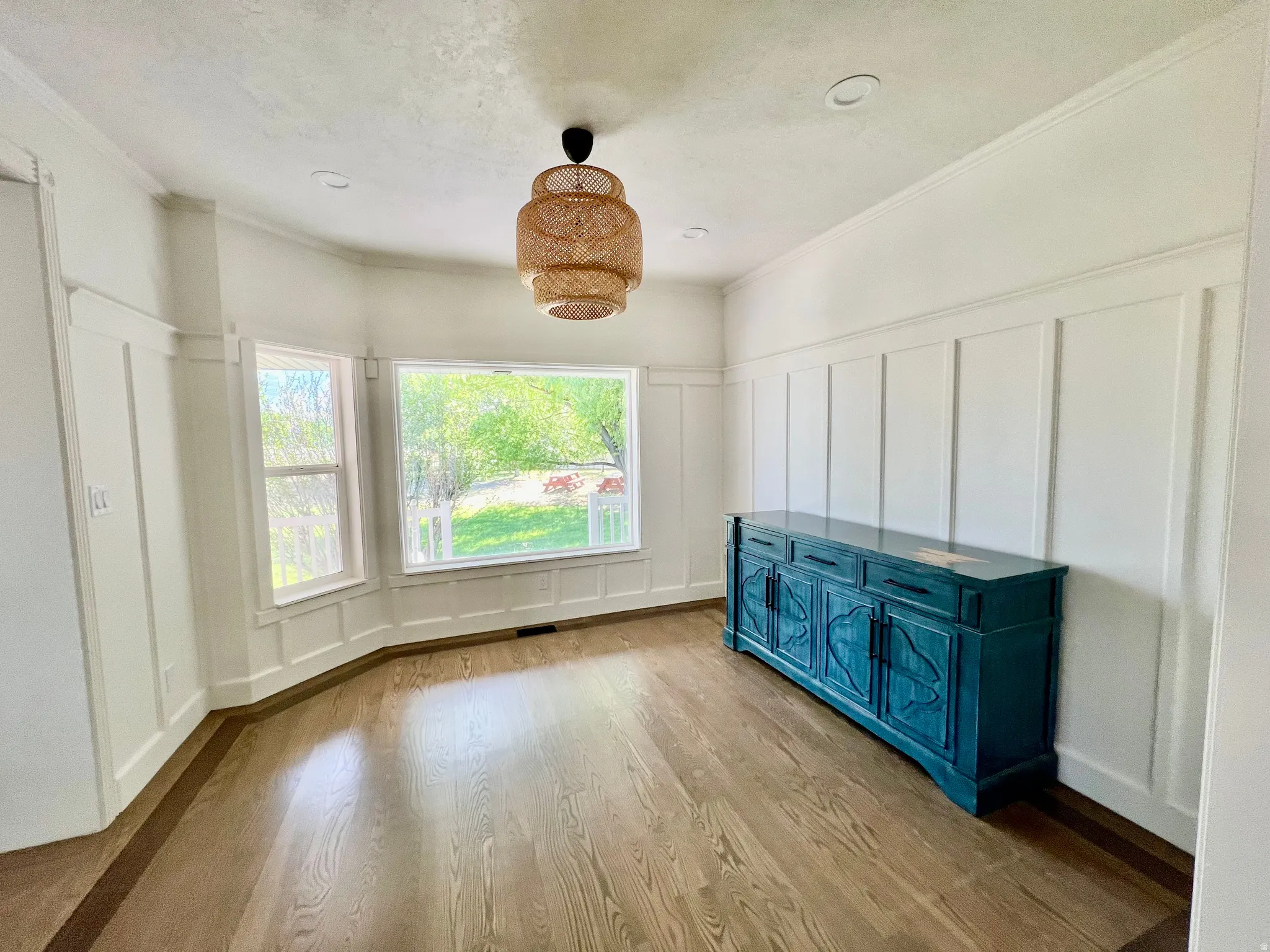 Dining area featuring natural wood-finish flooring with a contrasting border, board and batten wall detailing, and a multi-pane bay window