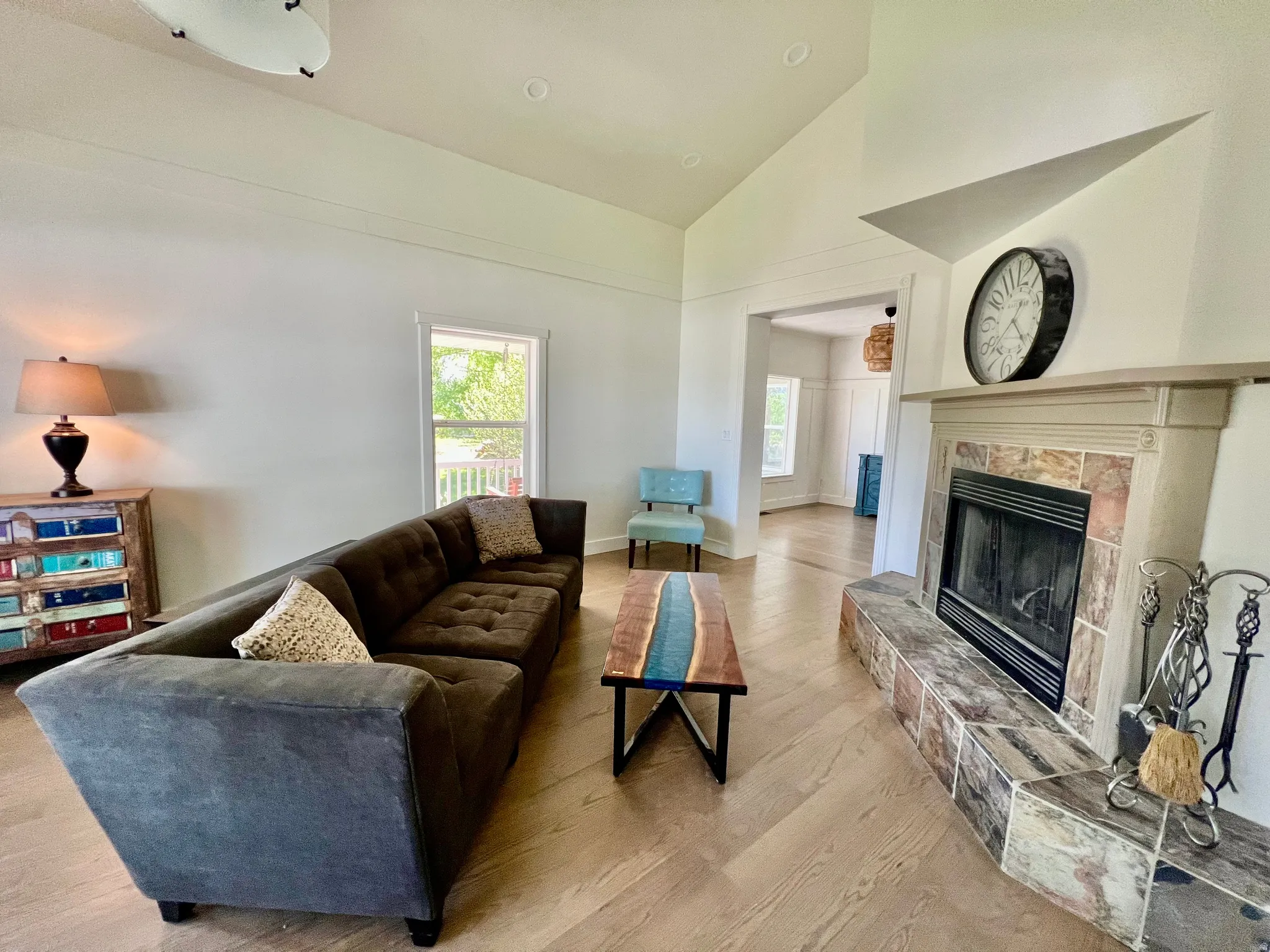 Living area featuring a fireplace with a tiled surround and hearth, wood-finish flooring, vaulted ceilings, and recessed lighting