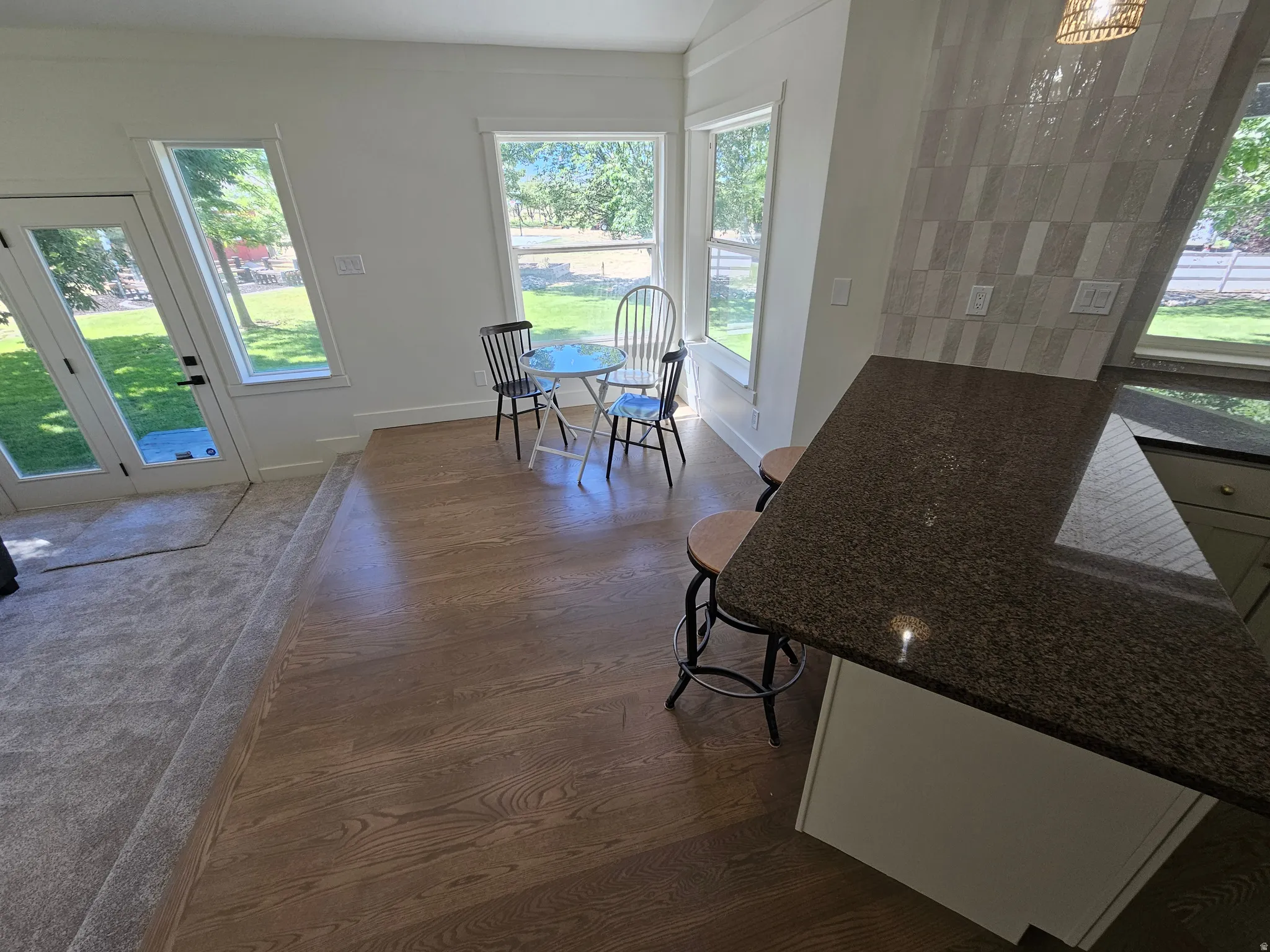Kitchen island with a dark granite countertop, light-toned cabinetry, and a patterned tile backsplash