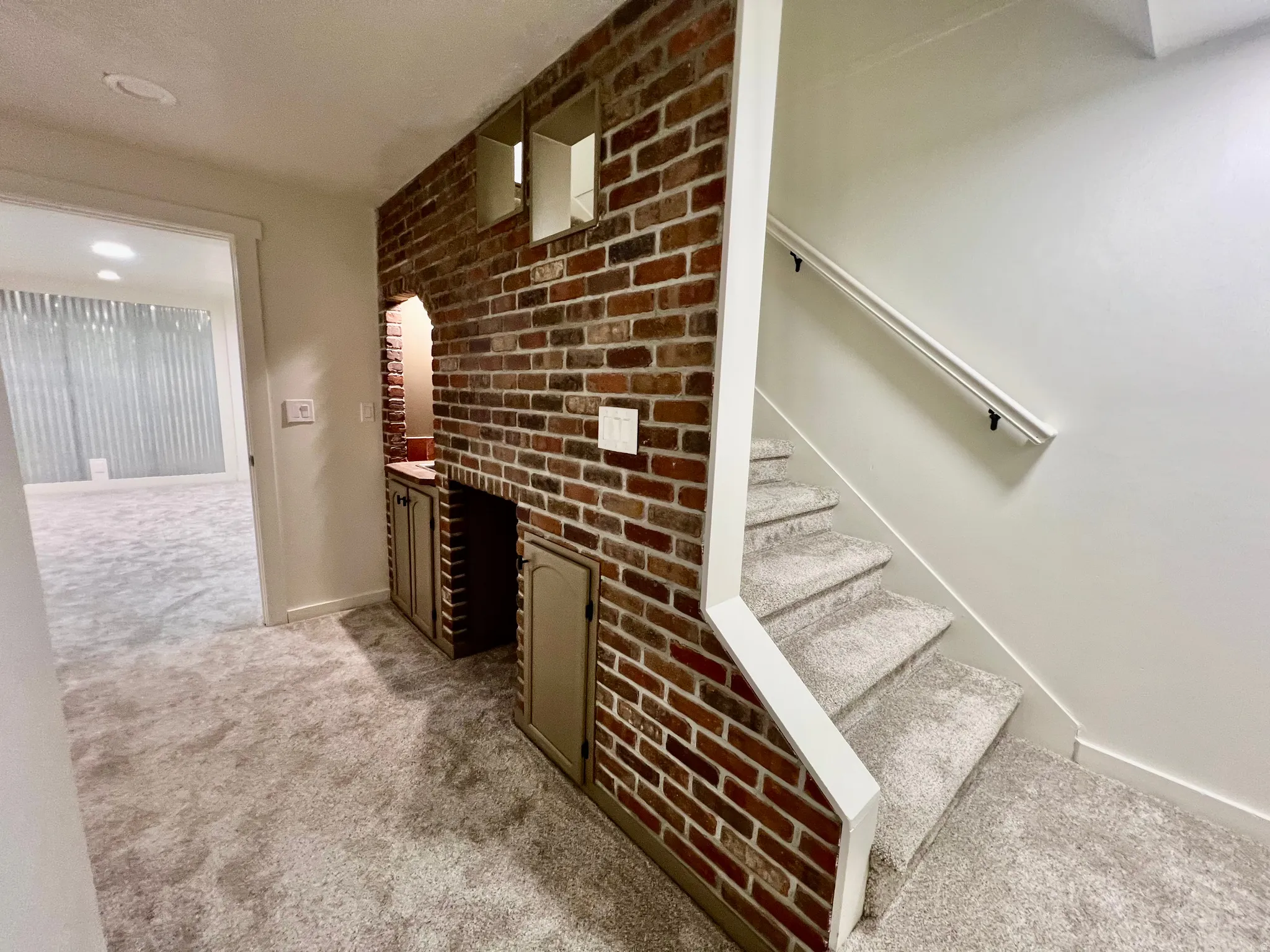 Brick accent wall with built-in cabinetry and recessed lighting