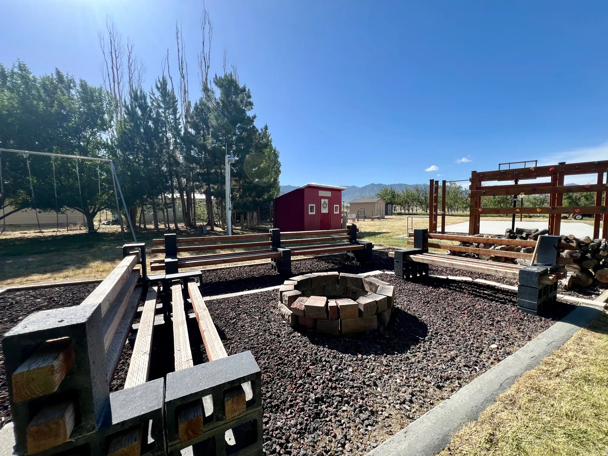 Outdoor area featuring a stone fire pit, built-in wooden benches on concrete block supports, and a gravel ground cover