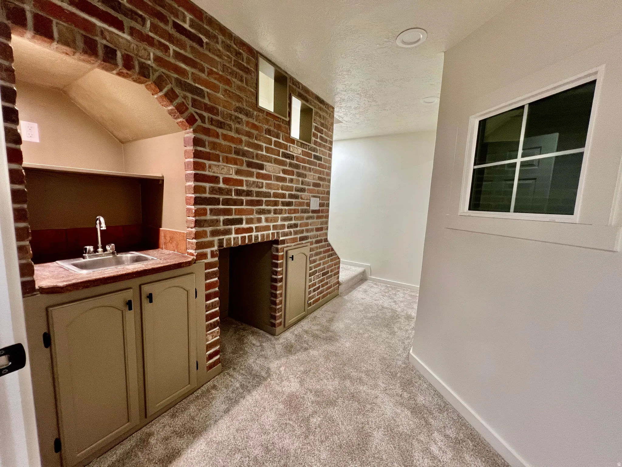 Built-in wet bar with a stainless steel sink, countertop, and lower cabinetry