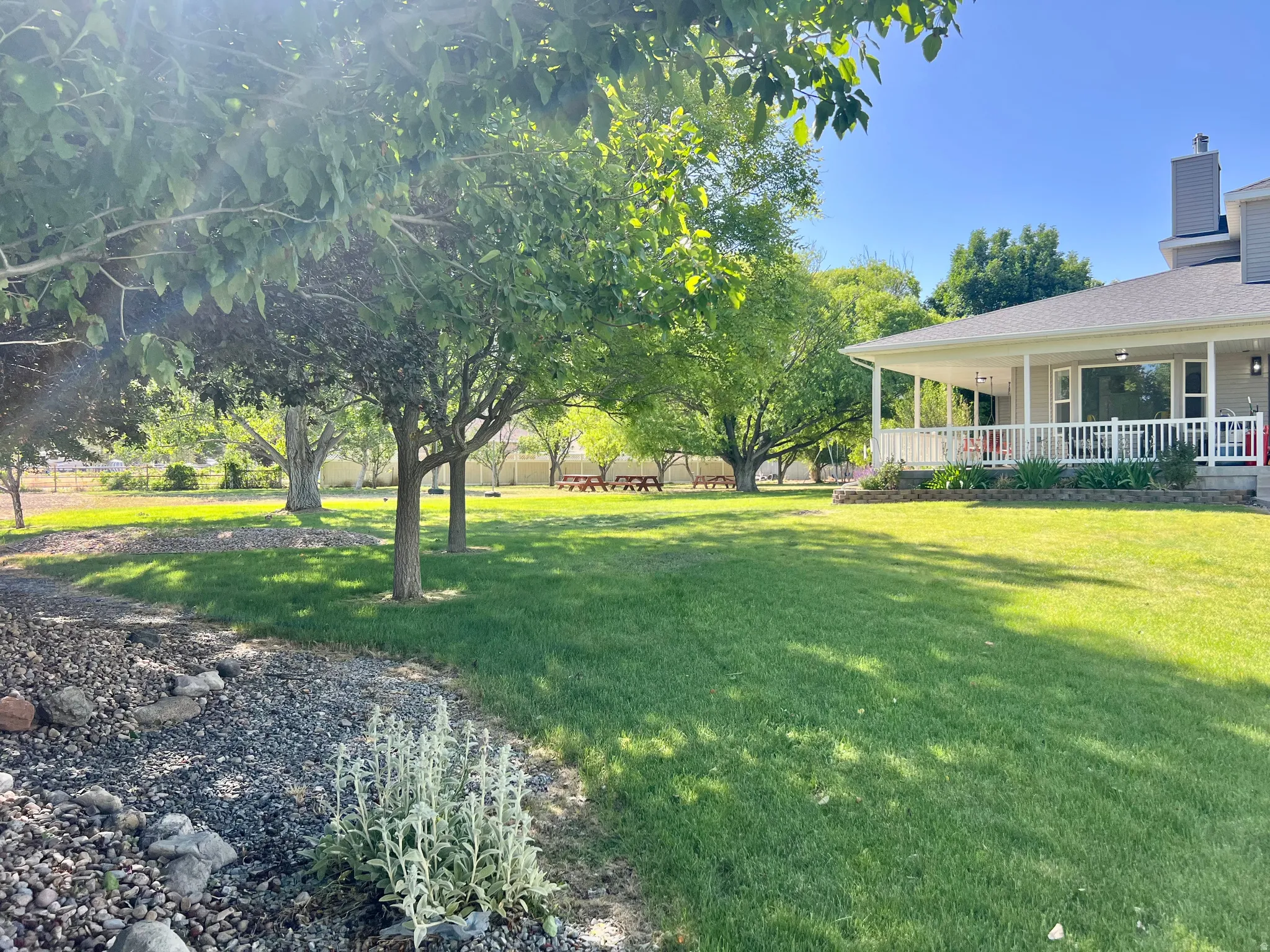 Expansive green lawn with mature trees and a covered porch
