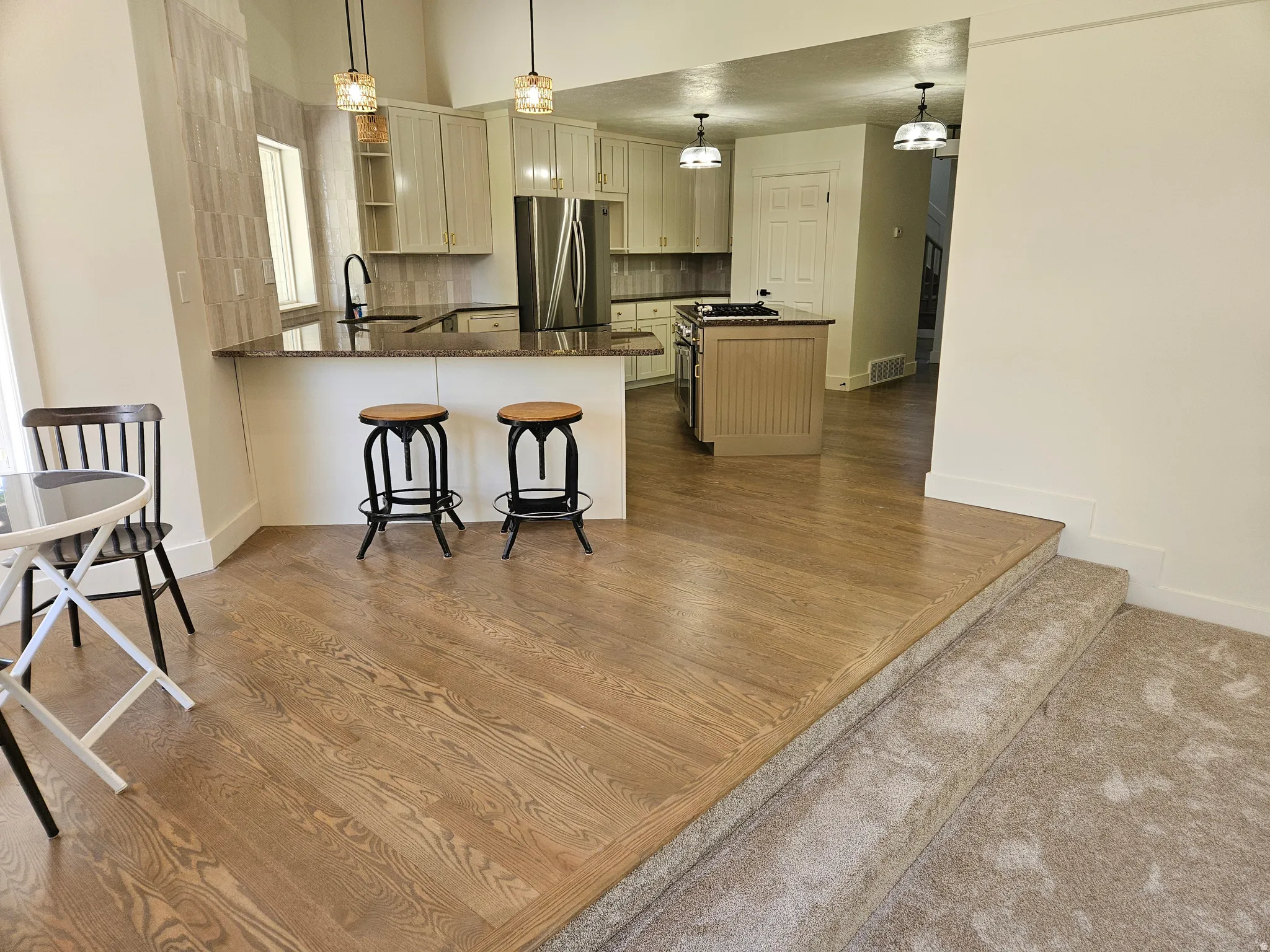 Contemporary kitchen featuring light cabinetry, dark countertops, a tile backsplash, and stainless steel appliances