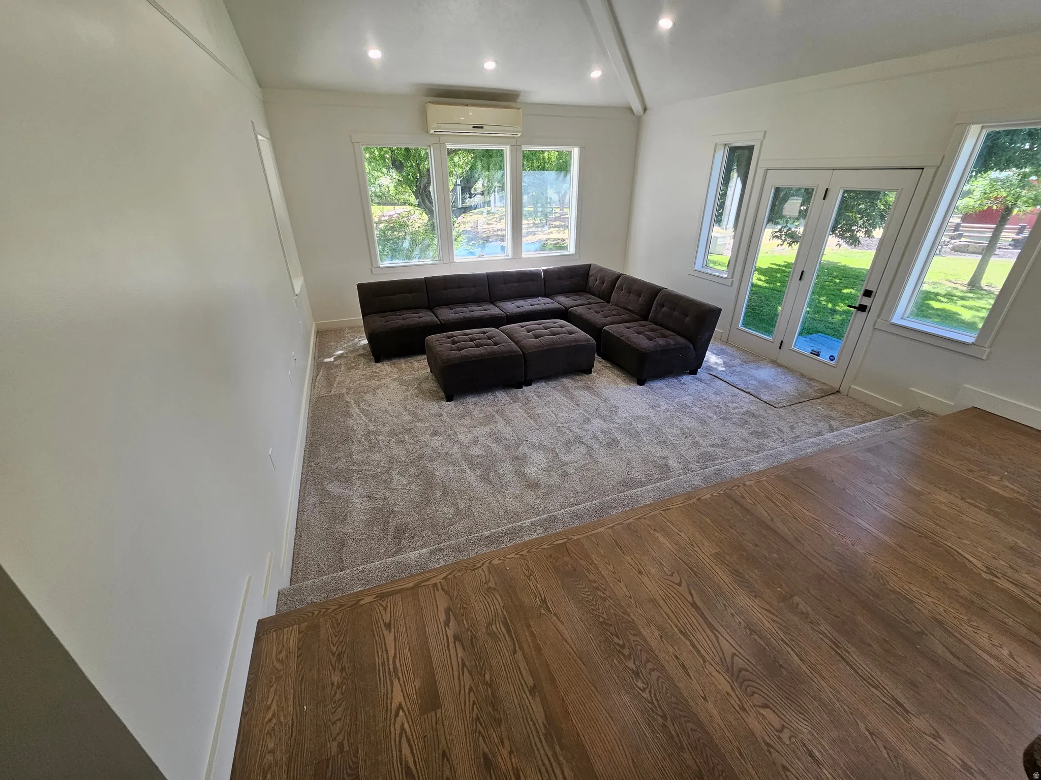 Sunlit living space featuring a vaulted ceiling with recessed lighting