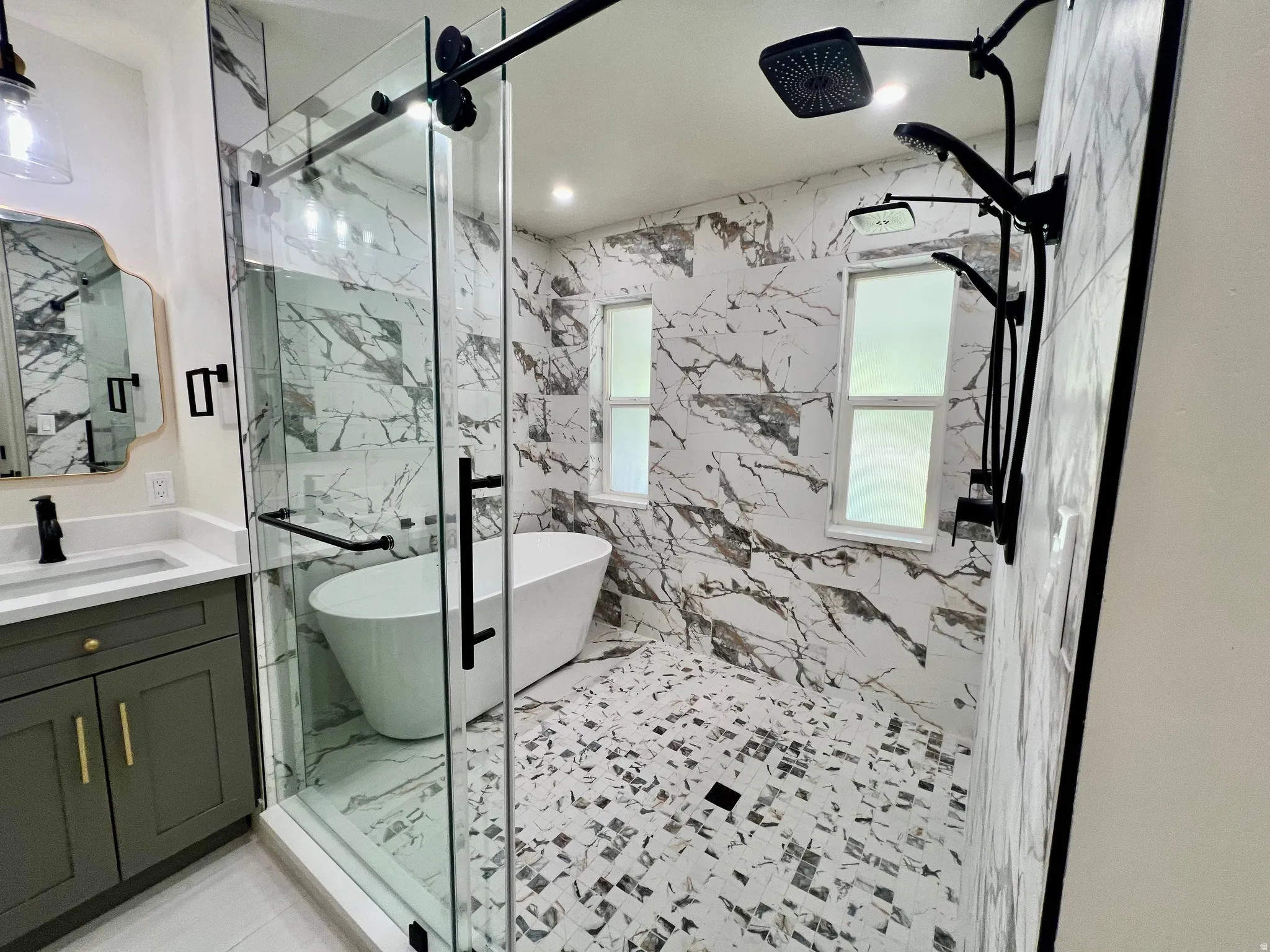 Expansive walk-in shower featuring a freestanding tub, floor-to-ceiling marble-look tile, and a multi-function matte black shower system