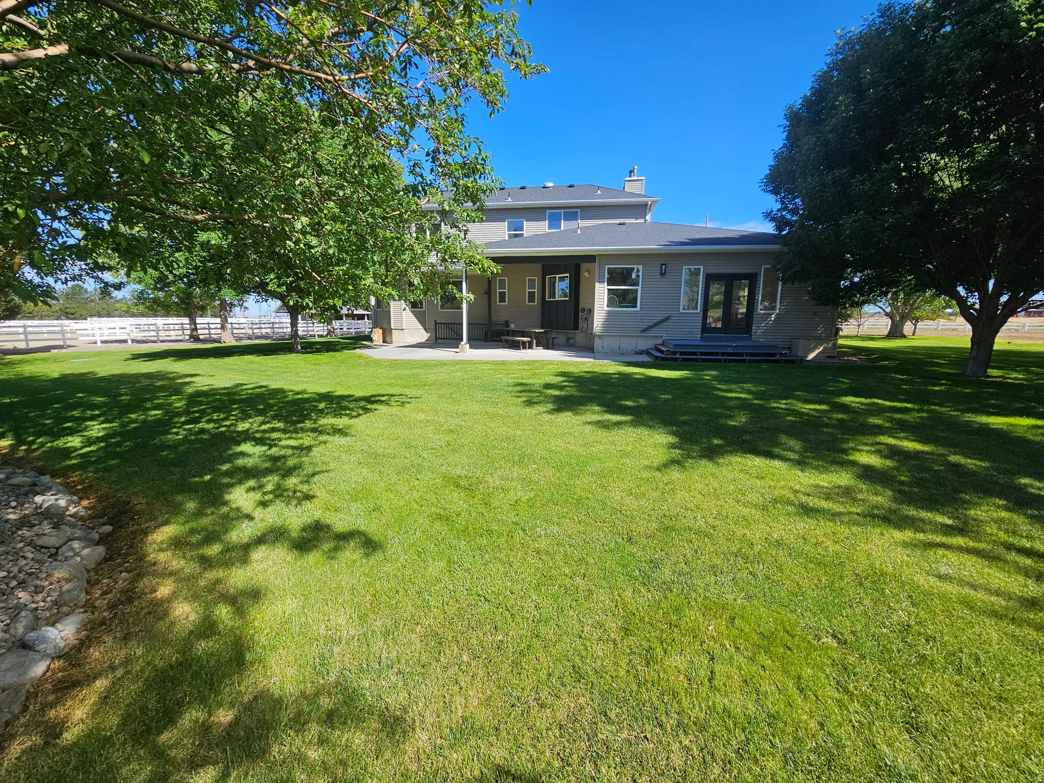 Expansive green lawn with mature shade trees and a stone-edged border