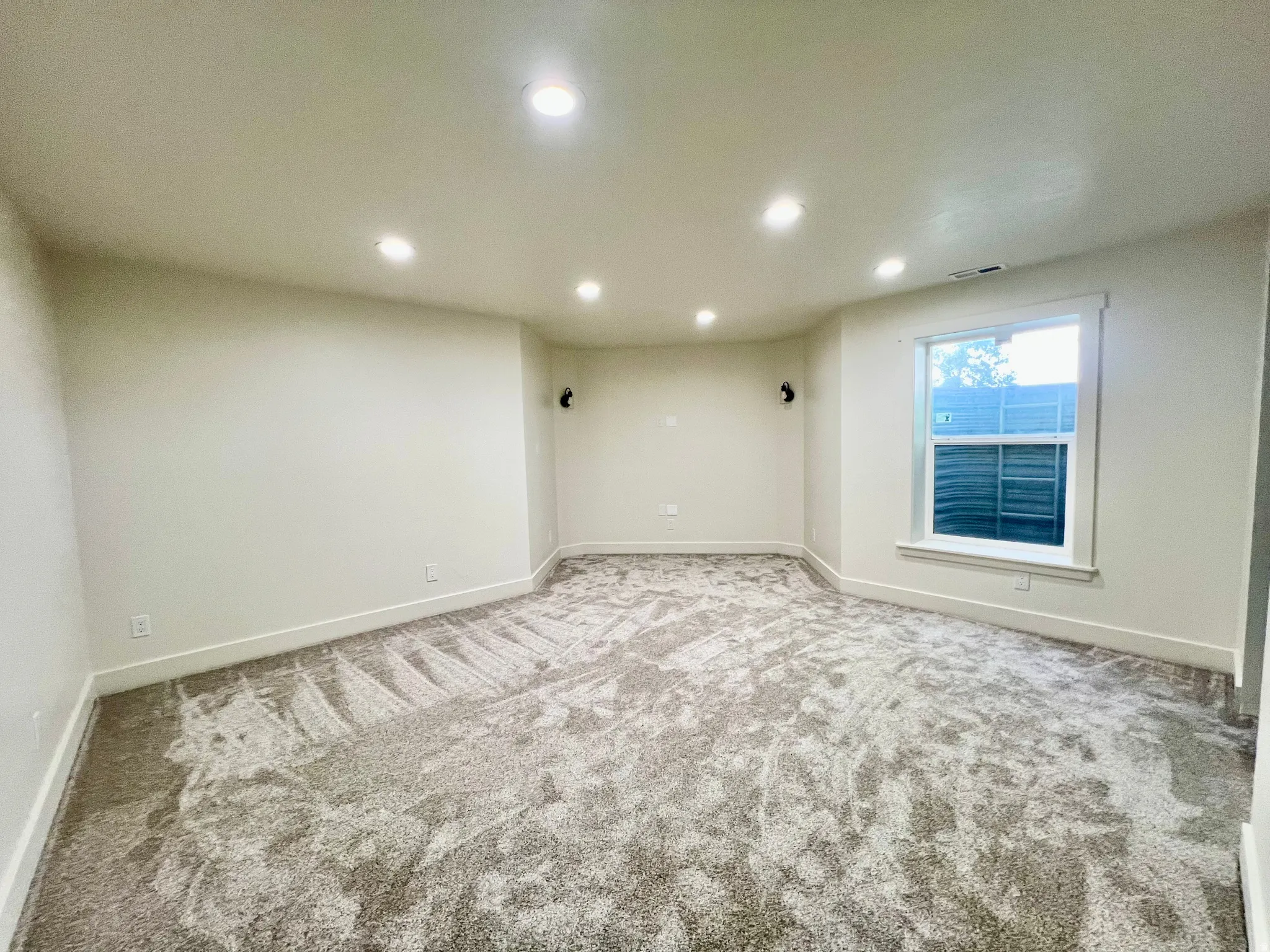 Spacious room featuring neutral carpeting, recessed ceiling lighting, a white trim window, and light-toned walls